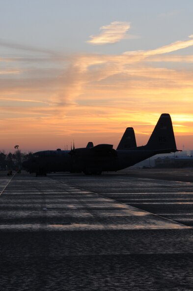 The sun rises over C-130 Hercules aircraft parked on the Ramstein Air Base flightline waiting for maintenance and the next mission Feb. 18, 2009.The C-130 serves primarily to perform the tactical portions of the missions. (U.S. Air Force photo by Airman 1st Class Caleb Pierce)