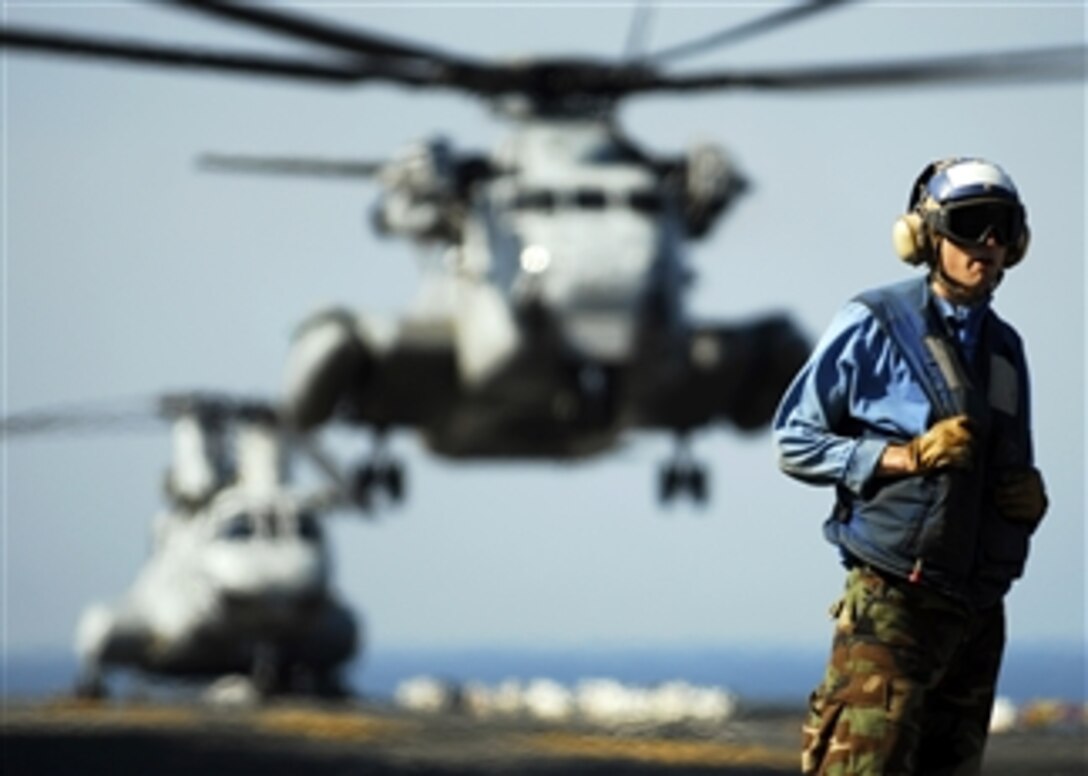 U.S. Navy Airman Patrick Neimeyer stands on the flight deck of the amphibious assault ship USS Essex (LHD 2) as a CH-53E Sea Stallion helicopter lands during exercise Cobra Gold 09 in the Gulf of Thailand on Feb. 15, 2009.  Cobra Gold is an annual joint-combined exercise conducted by military forces of the United States and Thailand to strengthen ties and prepare for possible contingencies in the region.  