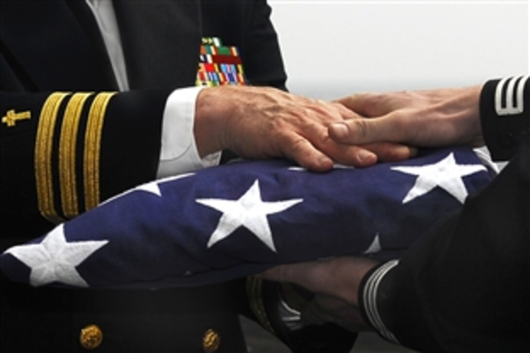 U.S. Navy Cmdr. Ronald Kawczynski hands a U.S. flag to U.S. Petty Officer 3rd Class David Swan, a religous program specialist, during a burial-at-sea ceremony aboard the aircraft carrier USS John C. Stennis in the Pacific Ocean, Feb. 16, 2009.
