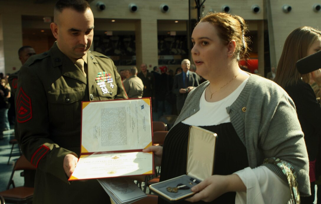 Shannon Yale and Gunnery Sgt. Sam Clark, a casualty assistance officer, glance over the Navy Cross citation and award which was awarded to Cpl. Jonathan T. Yale, posthumously. Yale was killed in action while guarding in post April 22, 2008, in Ramadi, Iraq, against a suicide bomber.