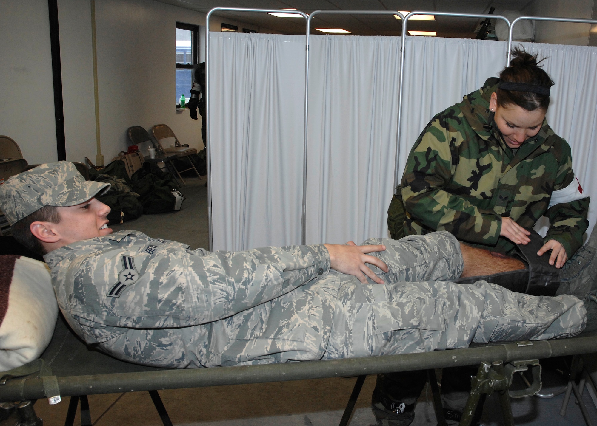 Senior Airmen Kristen Lynch, 88th Medical Operations Squadron medical technician, bandages the simulated fractured leg of Airman Joshua Bevins, 88th Diagnostics Therapeutic  Squadron laboratory technician, during a readiness exercise at Wright-Patterson Air Force Base.  The readiness exercise held Feb. 17-20 simulated the deployment of 150 Airmen to Manas Air Force Base, Kyrgyzstan.  