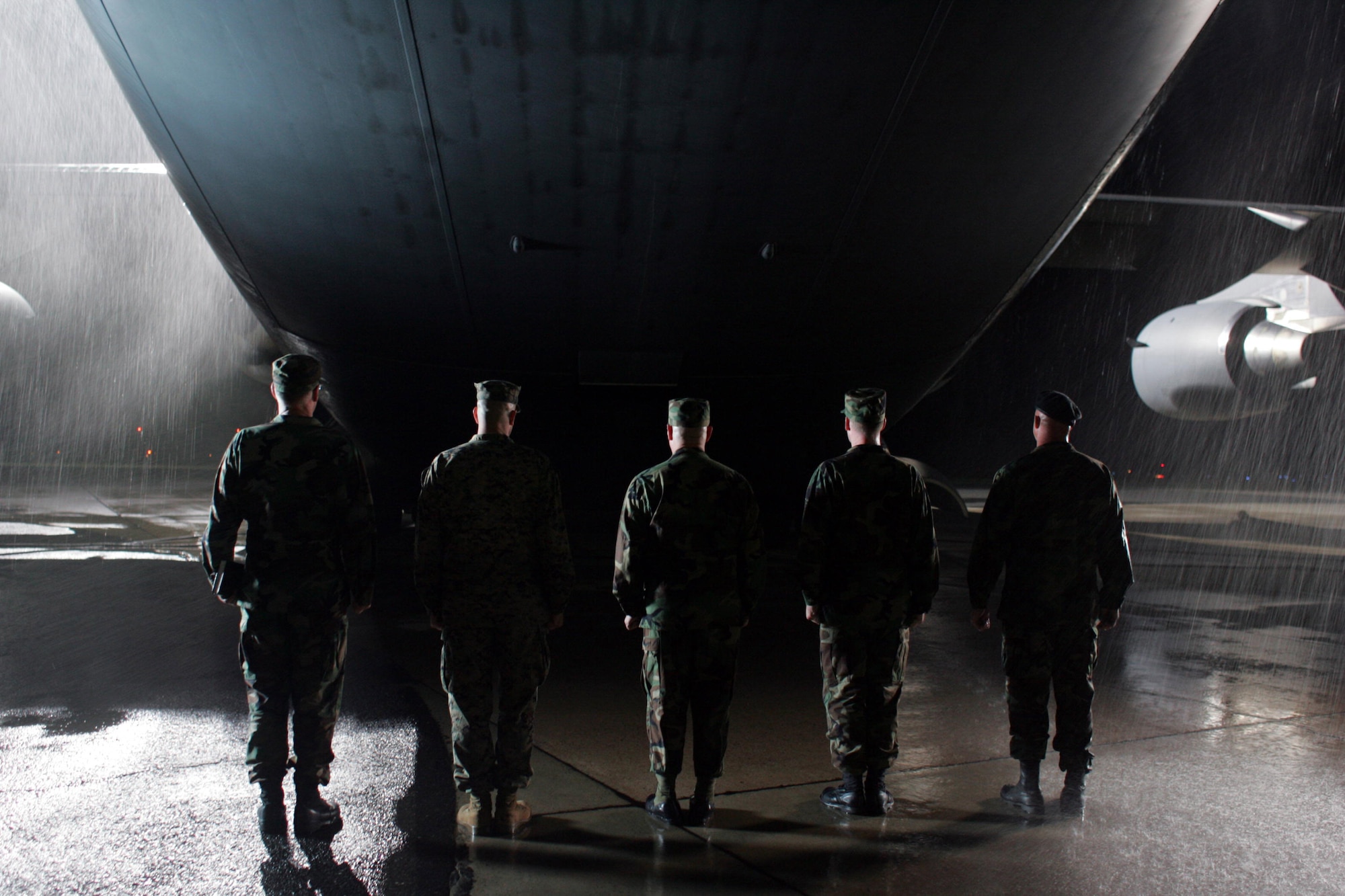 Airmen respectfully and silently wait for a C-17 to open at McGuire Air Force Base, N.J., as part of a scene for HBO's "Taking Chance" movie, which airs Feb. 21. The Airmen are portraying the dignified transfer party who would escort a fallen hero to the Dover Port Mortuary at Dover AFB, Del. Every fallen servicemember travels to Dover AFB for processing. More than 25 Airmen and 50 Marines in various locations served as extras and subject matter experts for the filming. The movie is based on the true story of Marine Lt. Col. Michael Strobl (ret) escorting a fallen lance corporal from Dover AFB to the lance corporal's hometown and final resting place, Dubois, Wyo. (Photo by James Bridges/HBO) 