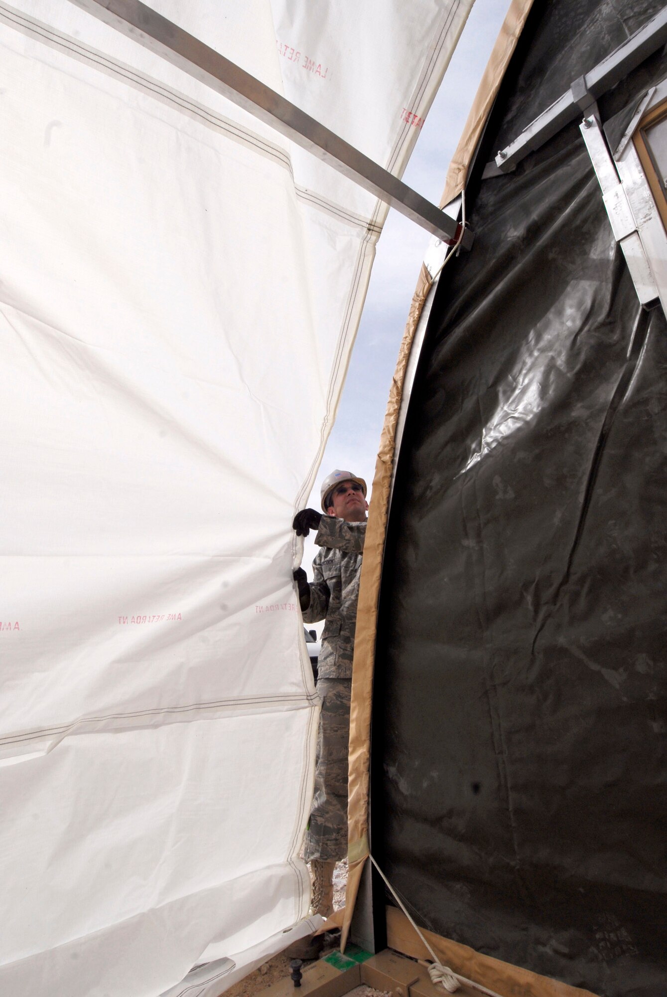 Airman 1st Class Michael Babcock ensures the skin for a California Medium Shelter System does not tear over the archway being covered Feb. 17 at an air base in Southwest Asia.  Airman Babcock is a structural journeyman with the 379th Expeditionary Civil Engineer Squadron.  He is from Sheridan, Mich., and is deployed from Dover Air Force Base, Del.  (U.S. Air Force photo/Airman 1st Class Andrew Satran)