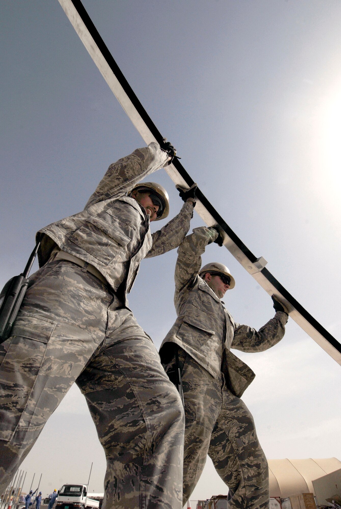 Staff Sgts. Matthew Cruz and Evan Bellamy raise an arch component Feb. 17 to finish the skeleton of a California Medium Shelter System which will be used to house Airmen at an air base in Southwest Asia. The NCOs are structural craftsmen with the 379th Expeditionary Civil Engineer Squadron.  Sergeant Cruz, from Tacoma, Wash., is deployed from Pope Air Force Base, N.C.  Sergeant Bellamy, from Sullivan County, N.Y., is deployed from Dover AFB, Del. (U.S. Air Force photo/Airman 1st Class Andrew Satran)
