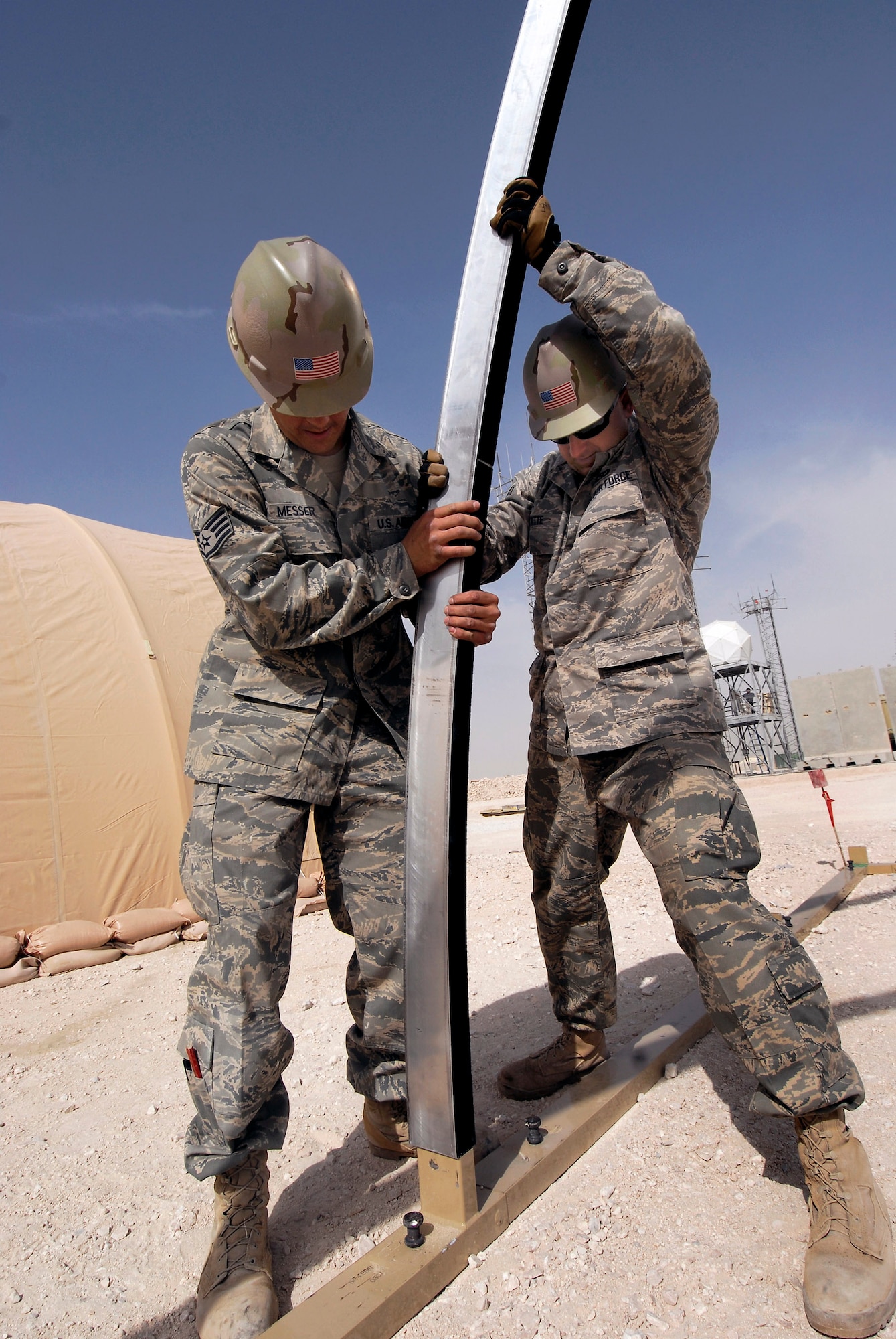 Staff Sgt James Messer (left) and Senior Airman Geoffrey Witte work an arch into the base of a California Medium Shelter System Feb. 17 used to house Airmen at an air base in Southwest Asia. The Airmen are structural craftsmen with the 379th Expeditionary Civil Engineer Squadron.  Staff Sgt. Messer, from Murphy, N.C., is deployed from Scott Air Force Base, Ill.  Airman Witte, from Anadarko, Okla., is deployed from Vandenberg AFB, Calif.  (U.S. Air Force photo/Airman 1st Class Andrew Satran) 