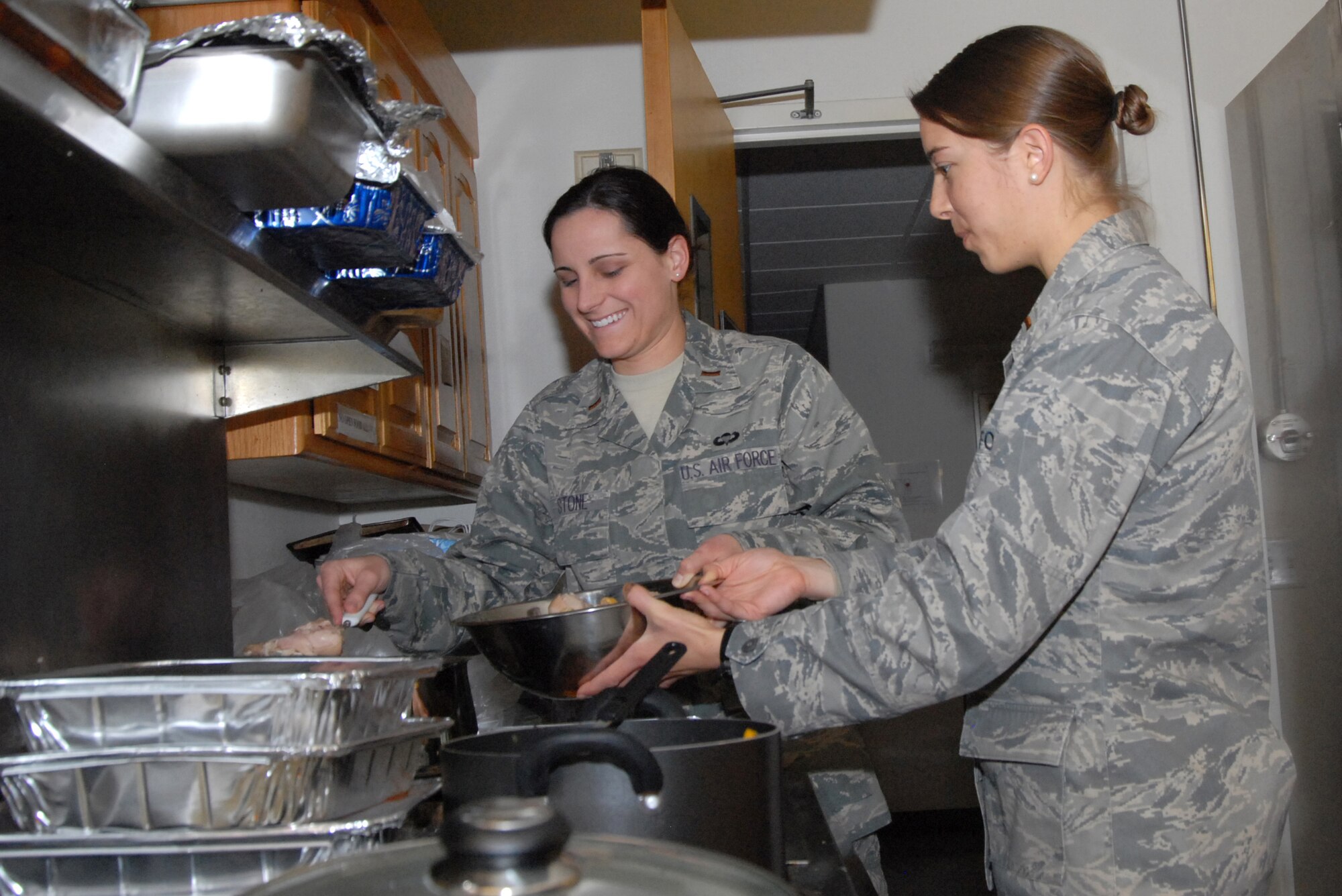 2nd Lt. Rebecca Stone (left), Air Force Research Laboratory research scientist and 2nd Lt. Christina McCool, 772nd Test Squadron test engineer, of the Company Grade Officers Council prepare food during a dorm dwellers dinner Feb. 18 at the Chapel 1 annex. Organizations such as the Edwards spouses clubs, Commissary and Club Muroc provided support for the event. (Air Force photo by 2nd Lt. Belena Stuart) 