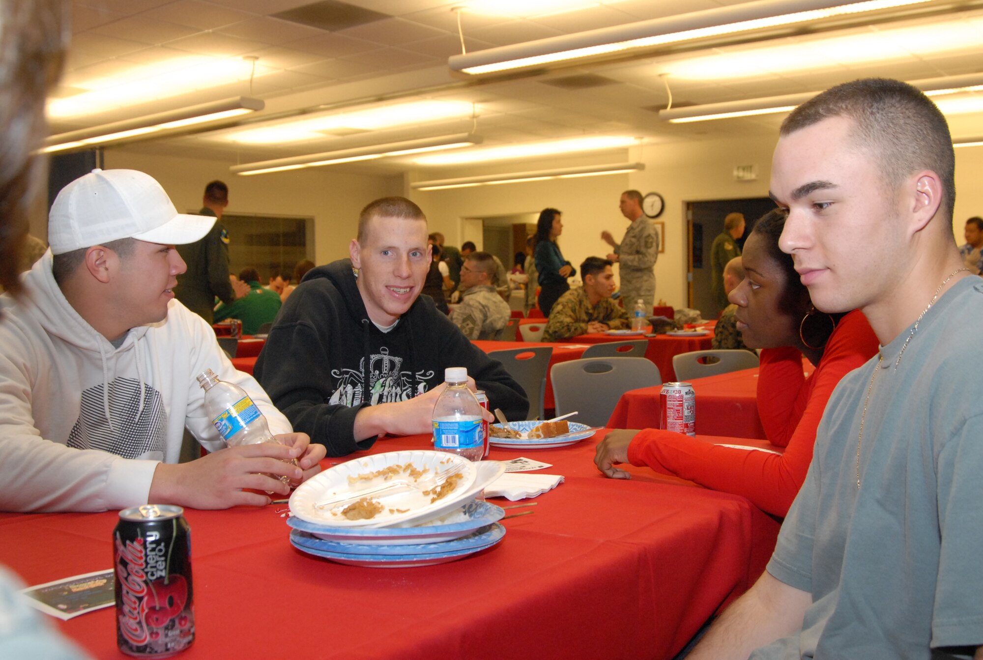 Airman1st Class Aaron Mendoza (left), 95th Security Forces Squadron, Airman1st Class Daniel Snook (center), 95th SFS, Airman 1st Class Melanie Rowell, Air Force Flight Test Center Staff Judge Advocate paralegal and Airman 1st Class Christopher McCaul (right) 95th SFS airman, talk during a dorm dwellers dinner at the Chapel 1 annex Feb. 18. The event was open to both Airmen and Marines who live in the dorms, offering them a free home-cooked meal. (Air Force photo by 2nd Lt. Belena Stuart) 