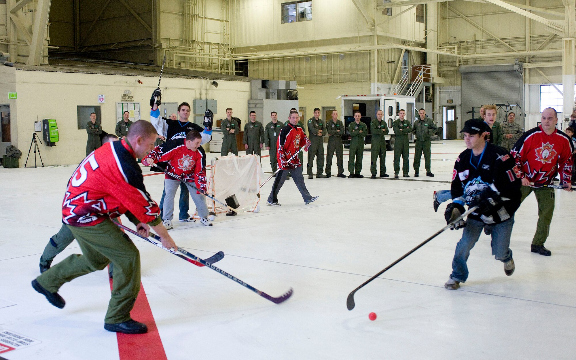 ELMENDORF AIR FORCE BASE, Alaska -- Canadian air force Master Cpl. Tim McClain, 962nd Airborne Air Control Squadron, and Alaska Aces hockey player Alexandre Imbeault lunge for the puck during a game Feb. 19, 2009. Officials from the 962nd AACS invited the Aces players to tour the 962nd AACS facility, the AWACS hangar and an E-3 Sentry before the friendly competition. Both Canadian and U.S. Air Force members of the 962nd made up squadron team. (U.S. Air Force photo/Senior Airman Jonathan Steffen)