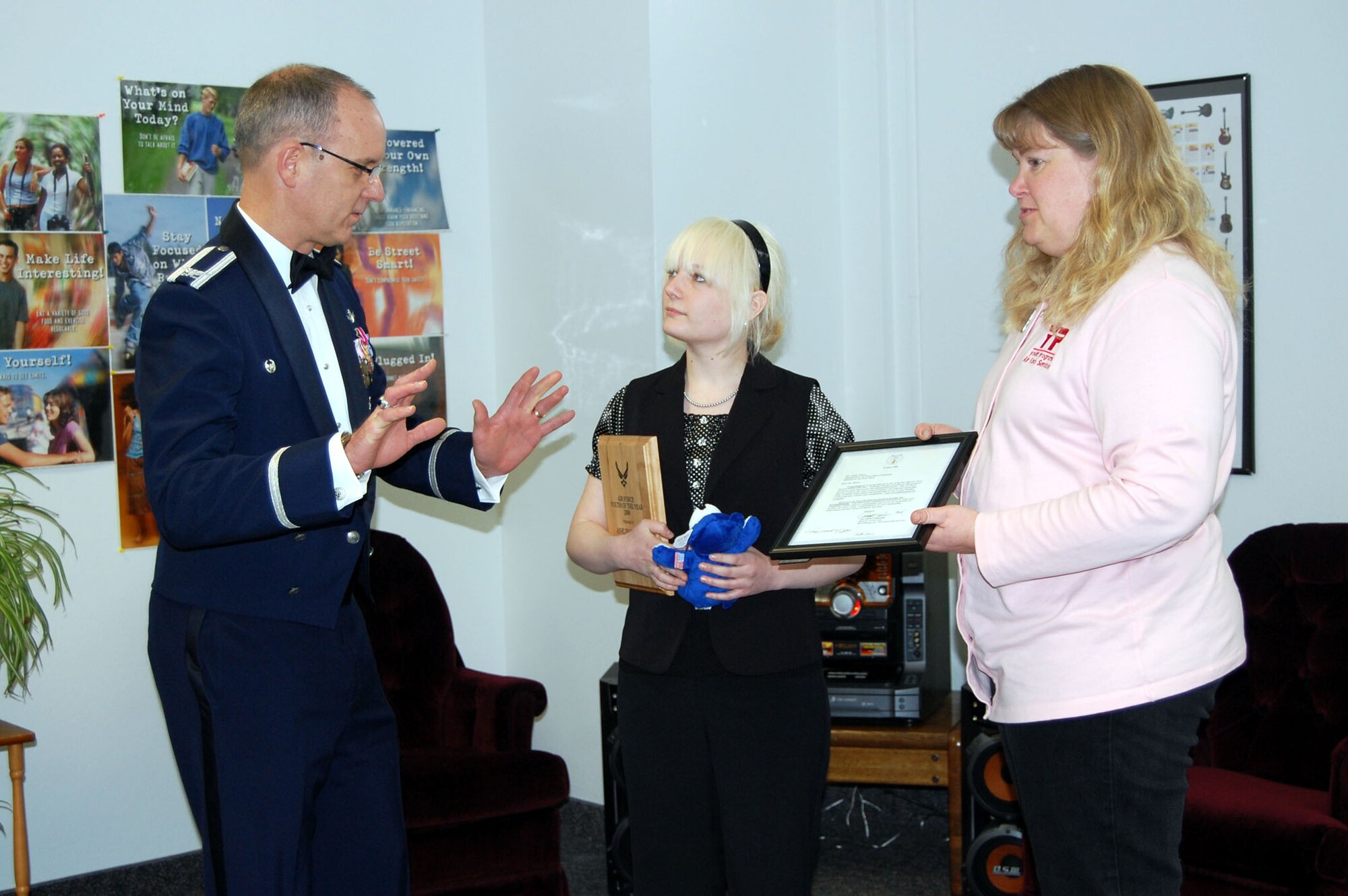 Ashley Morre, 16, listens to Col. Michael Fortney's advise for success in the future as Cindy Berg waits to present Ashley with another plaque. The 341st Missile Wing commander was at the Youth Center Feb. 11 to present Ashley with the Boys and Girls Club of America Youth of the Year award for Malmstrom. Ms. Berg is the Youth Center director. (U.S. Air Force photo/Valerie Mullett)