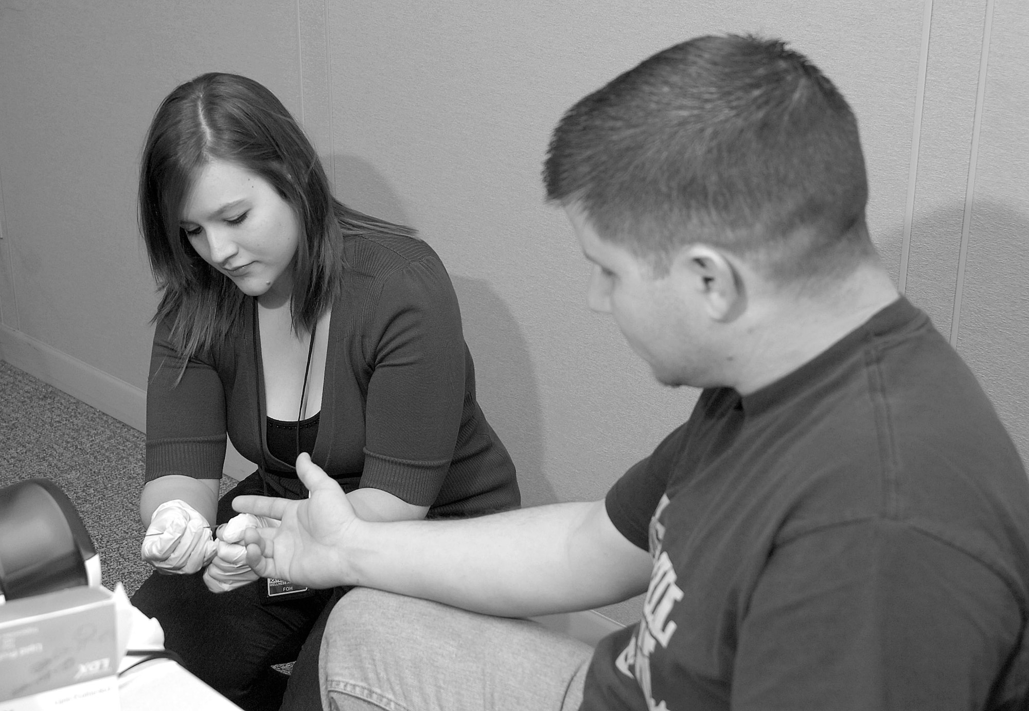 During a New Employee Orientation, wellness associate Kaylee Messec of the Civilian Health Promotion Services, takes blood from Michael Rennie, a new employee of the 565th Aircraft Maintenance Squadron. (Air Force photo/Margo Wright)