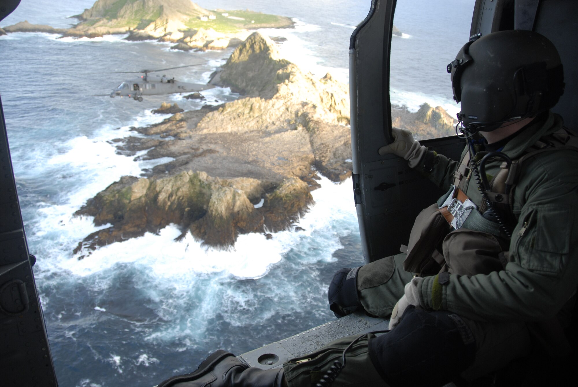 Staff Sgt. Andrew Hedin, flying in an HH-60G Pave Hawk helicopter, observes another Pave Hawk over Farallon Island, which sits some 30 miles west of San Francisco.   The helicopters and their crews, from the California Air National Guard's 129th Rescue Wing at Moffett Federal Airfield, Calif., are supporting the U.S. Fish and Wildlife Service by helping transport new photovoltaic batteries to power a lighthouse and workshop at the FWS research facility on the island.  Sergeant Hedin is an HH-60G flight engineer with the 129th RQW.   (U.S. Air Force photo/Tech. Sgt. Ray Aquino)