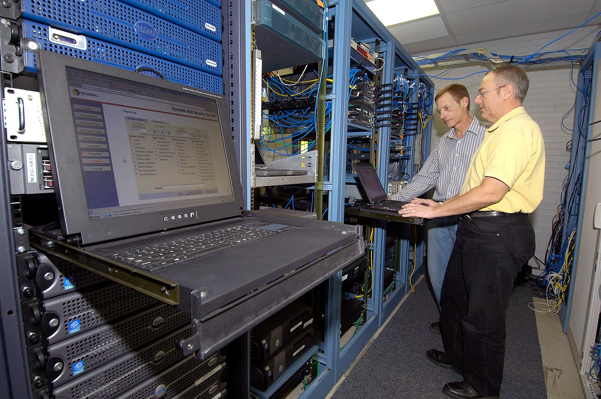 Firewalls, servers, routers and proxies are the business of 72nd Communications Squadron Network Security Office personnel  Randy Donner, front, and Dale Seymour.  A  crew of five takes care of the Tinker network perimeter, keeping customers hooked to the outside world without compromising security. It is an hourly “balancing act between security and speed,” said Mr. Donner.  They also act as middlemen between the command, the Air Force and base users.  “We help block thousands of attempts daily to infiltrate the network from across the country to other countries,” said Mr. Donner. “We try to make new (security) processes as seamless as possible to our customers.” (Air Force photo/Margo Wright)