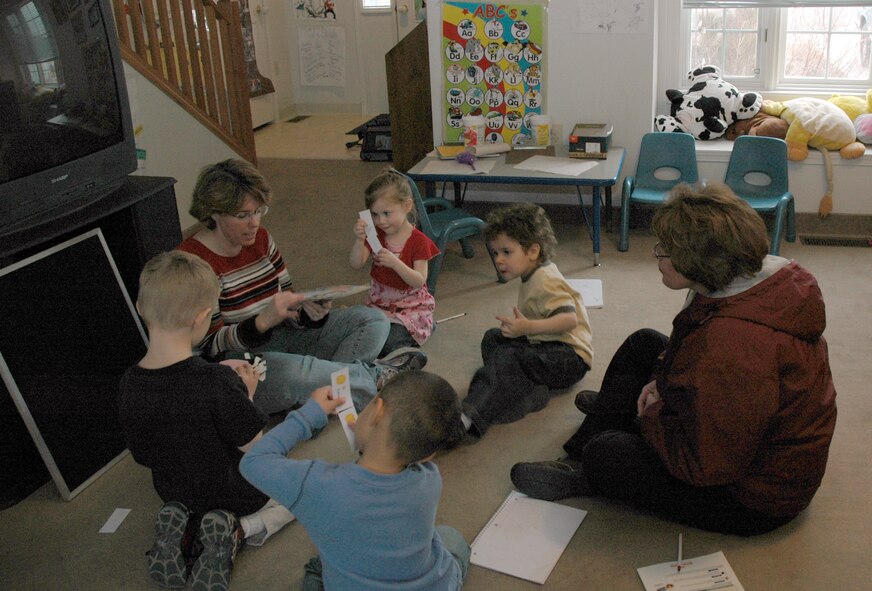 Family Child Caregiver Maggie Walters (left) gets ready to read a story to her four charges Feb. 11. Counter clockwise from left are Colin, 4; Sy, 4; FCC Director Margie Hahn; Keenan, 4; and Kyleigh, 3. (U.S. Air Force photo/Valerie Mullett)
