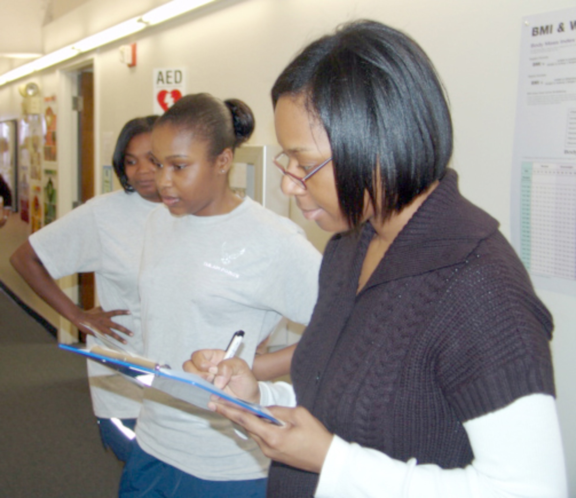 EGLIN AIR FORCE BASE, Fla. - Staff Sgt. Monique Hatcher and Senior Airman Sade Leonard, members of Team Chief's Angels, 46th Maintenance Group, look on as Michelle May, health promotions assistant, looks over information gathered on the team members. The first day of Team Lean Challenge and a fitness expo at the HAWC drew teams from across base. (U.S. Air Force photo/Noel Getlin)