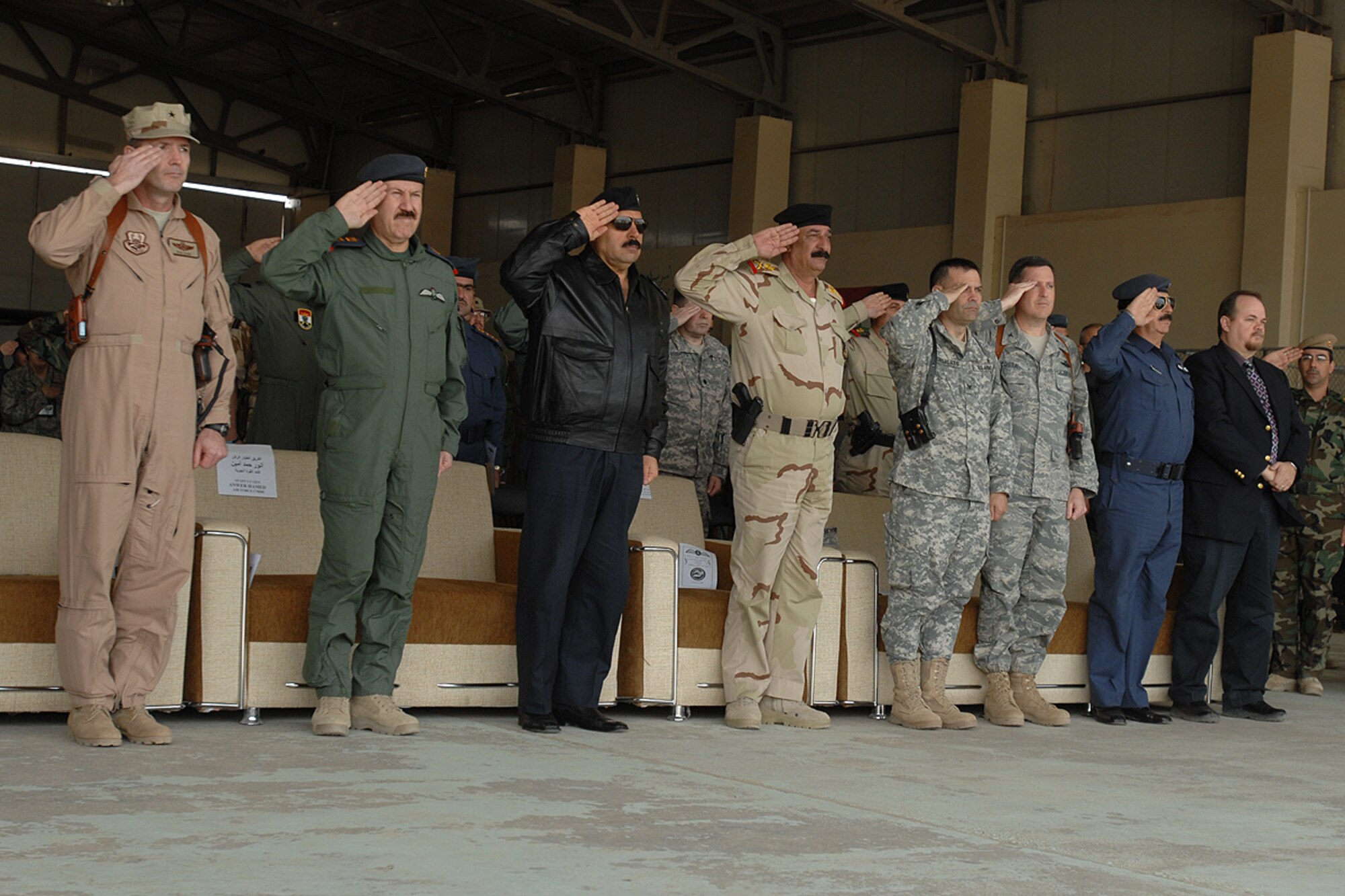 KIRKUK REGIONAL AIR BASE, Iraq – Brig. Gen. Robert Kane, Coalition Air Force Transition Team commanding general, and Lt. Gen. Anwar Hamad Amen Ahmed, Iraqi Air Force commander, along with other U.S. and Iraqi Air Force leaders render courtesies to the playing of the Iraqi and American national anthems during the Iraqi Air Force pilot graduation ceremony here Feb. 19. There were fourteen Iraqi pilots and instructor pilots honored during the ceremony.  (U.S. Air Force photo / Senior Airman Eunique Stevens)