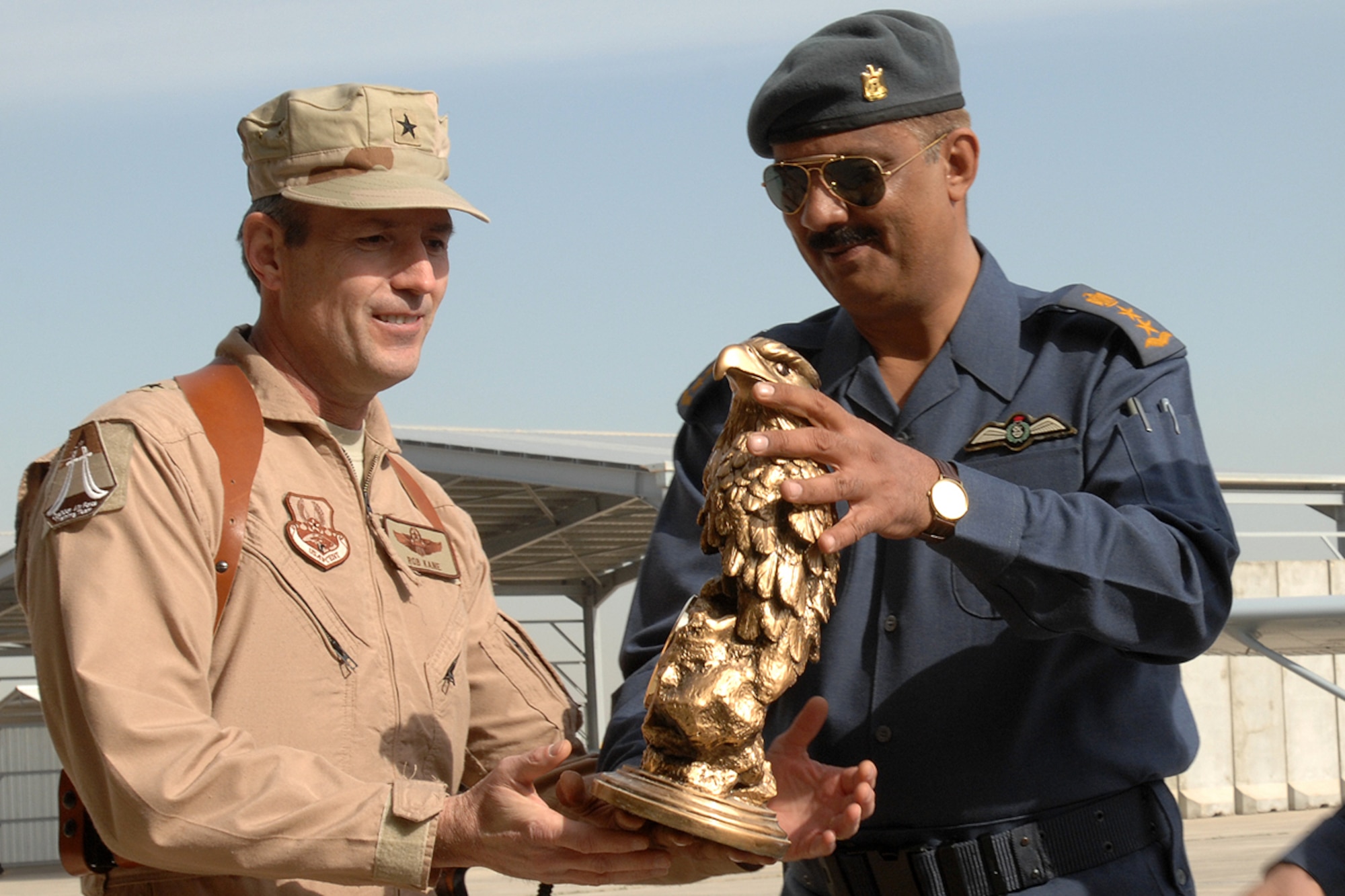KIRKUK REGIONAL AIR BASE, Iraq – Brig. Gen. Robert Kane, Coalition Air Force Transition Team commanding general, and Lt. Gen. Anwar Hamad Amen Ahmed, Iraqi Air Force commander, along with other U.S. and Iraqi Air Force leaders render courtesies to the playing of the Iraqi and American national anthems during the Iraqi Air Force pilot graduation ceremony here Feb. 19. There were fourteen Iraqi pilots and instructor pilots honored during the ceremony.  (U.S. Air Force photo / Senior Airman Eunique Stevens)