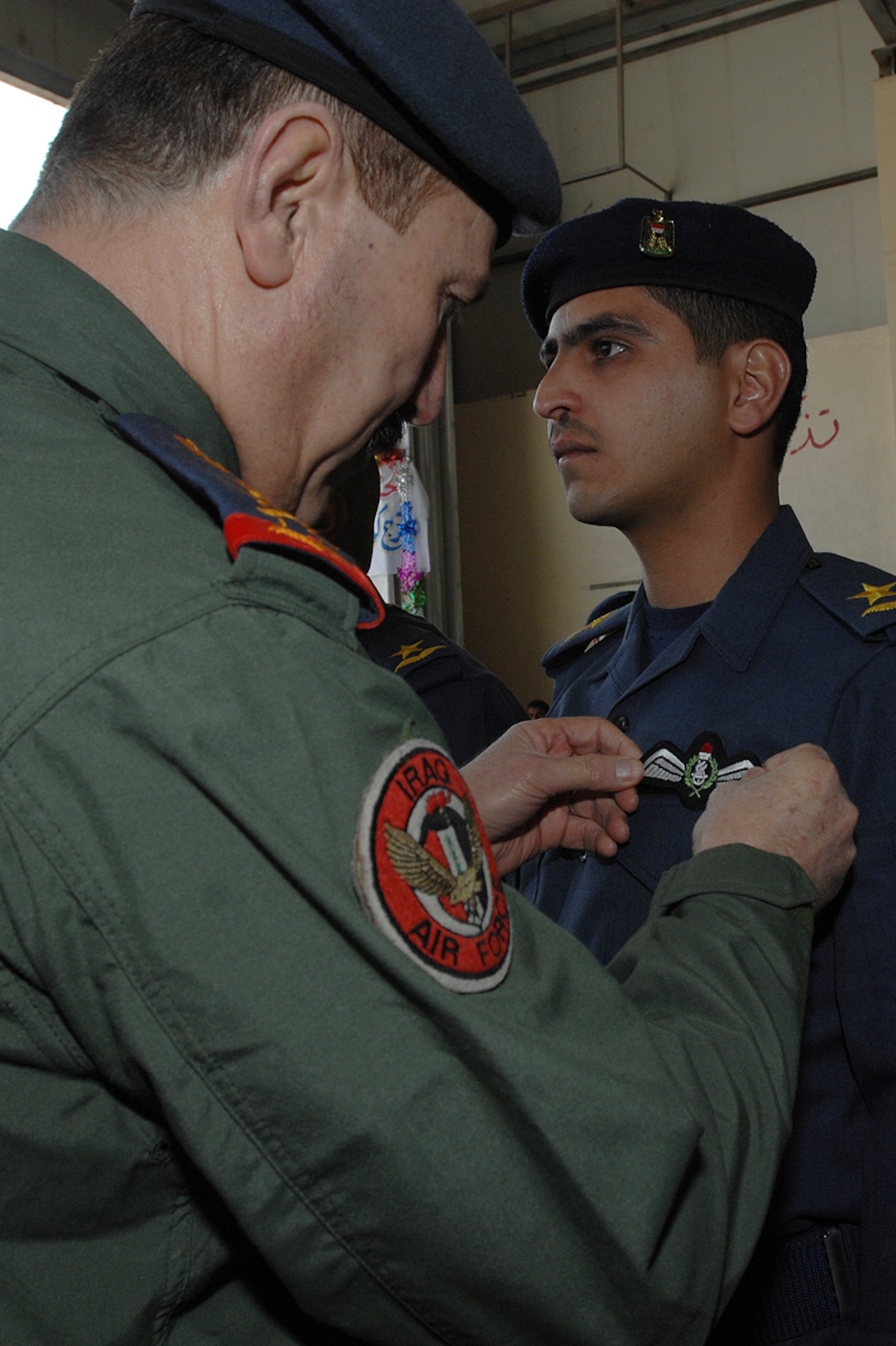 KIRKUK REGIONAL AIR BASE, Iraq – Lt. Gen. Anwar Hamad Amen Ahmed, Iraqi Air Force commander, pins wings on a pilot during the Iraqi Air Force pilot graduation ceremony here Feb. 19. Nine Iraqi pilots received their wings during the ceremony. (U.S. Air Force photo / Senior Airman Eunique Stevens)
