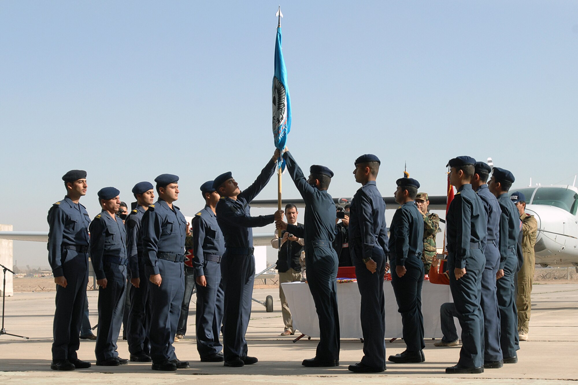 KIRKUK REGIONAL AIR BASE, Iraq –Graduating student pilots from the Iraqi Air Force Flying Training Wing pass the wing’s flag to the new senior class during the Iraqi FTW’s graduation ceremony here Feb. 19. Nine Iraqi pilots received their wings and five airmen became instructor pilots. (U.S. Air Force photo / Senior Airman Eunique Stevens)