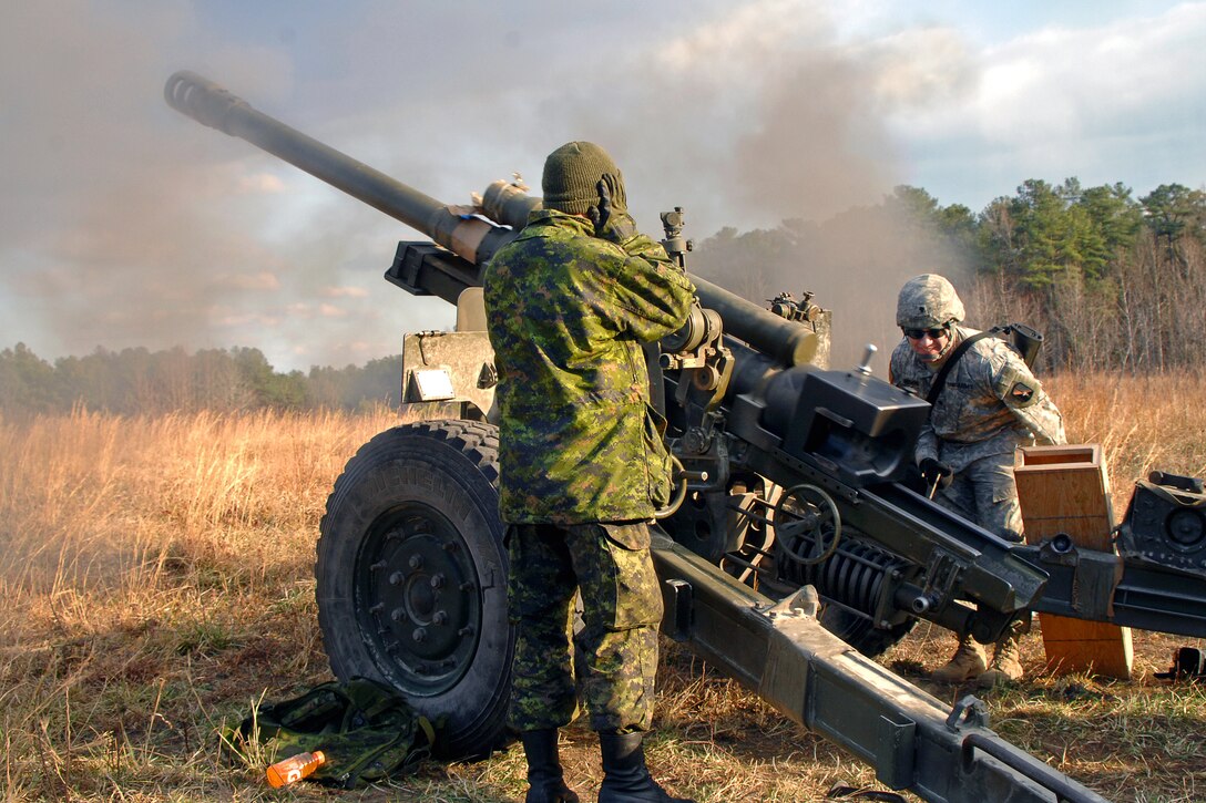 U.S. Army Spc. Christopher Rosario fires a C3 105mm howitzer during Exercise Southbound Trooper IX as Michael Habb, a bombardier from the Canadian 1st Field Artillery Regiment, 36 Canadian Brigade Group, observes on Fort Pickett, Va. Feb. 16, 2009. Rosario is assigned to the 55th Signal Company, Combat Camera.