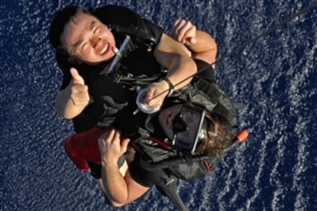 U.S. Navy Petty Officer 2nd Class Kelvin Y. Chen and Petty Officer 2nd Class Kevin M. Abney, search and rescue swimmers assigned to USS Blue Ridge, get pulled from the water by an SH-60F Seahawk rescue hook during a training scenario in the Pacific Ocean, Feb. 18, 2009.
