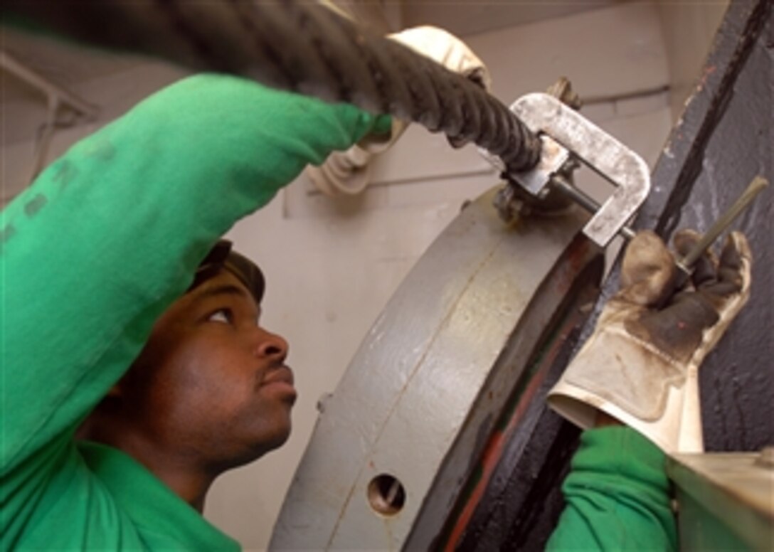 U.S. Navy Petty Officer 3rd Class Willie Moore lets the slack out of an arresting gear cable aboard the aircraft carrier USS Theodore Roosevelt (CVN 71) while the ship is underway in the Gulf of Oman on Feb. 14, 2009.  The ship and embarked Carrier Air Wing 8 are operating in the U.S. 5th Fleet area of responsibility.  