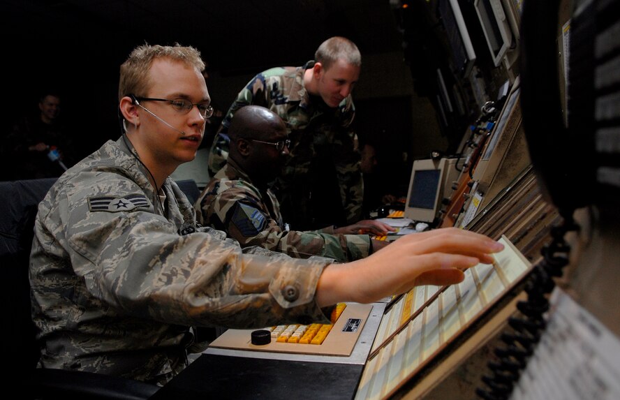 Senior Airman Joseph Hatfield reaches for a flight progress strip as he controls aircraft from radar approach control Feb. 18 at Osan AB, Republic of Korea.  The RAPCON controls aircraft landing at altitudes almost 14,000 feet and a 40-mile radius from the base.  Senior Airman Hatfield is an air traffic controller with the 51st Operations Support Squadron. (U.S. Air Force Photo/Staff Sgt. Brian Ferguson)