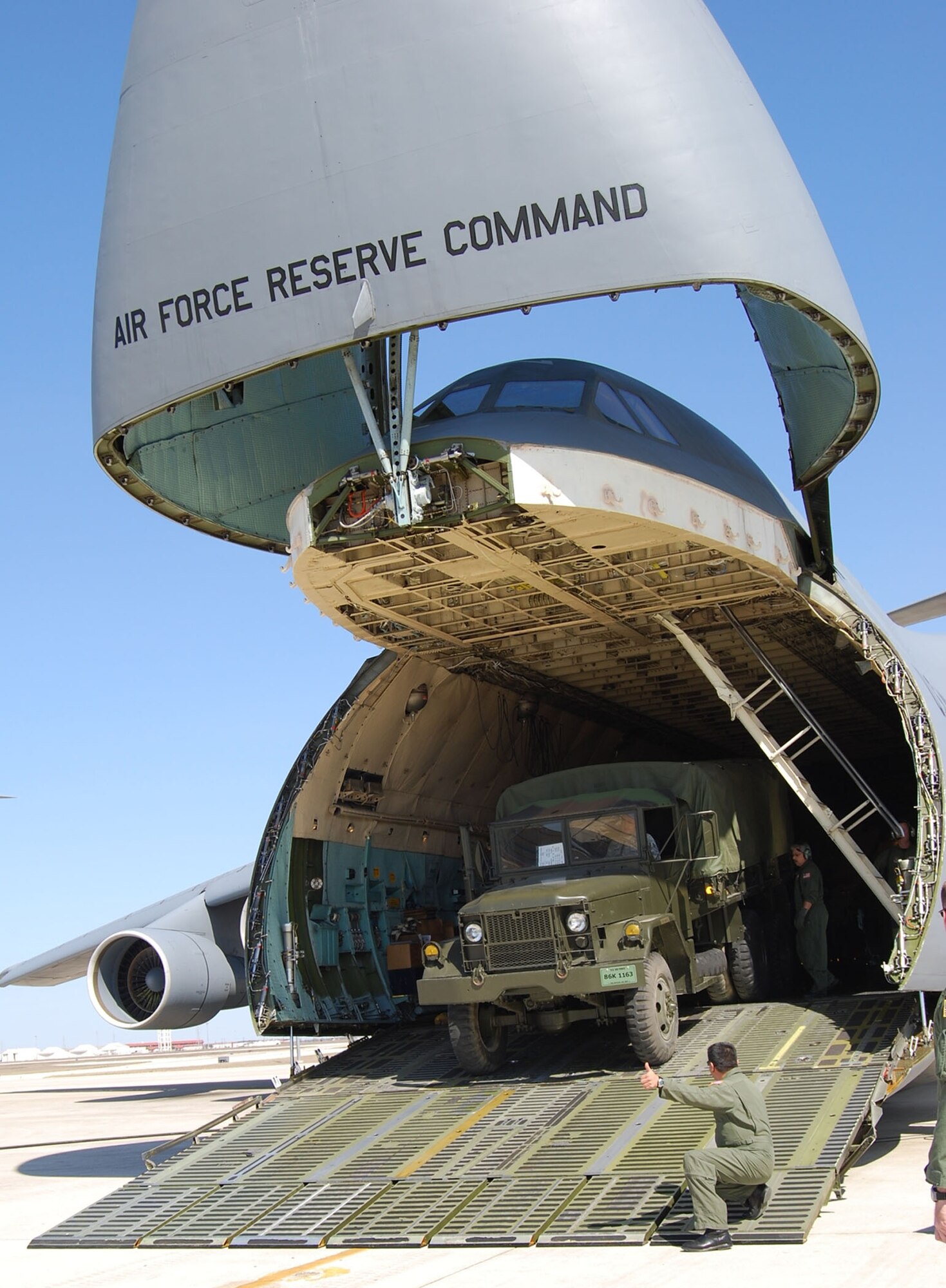 Chief Master Sergeant Al Moreno, the chief load master of the 68th Airlift Squadron, signals the all clear for a driver to drive a 2.5 ton truck out of the cargo bay of one of the Alamo Wing's C-5A Galaxy aircraft during a demonstration for local clergy. (U.S. Air Force Photo/Senior Airman Carrie Peasinger)