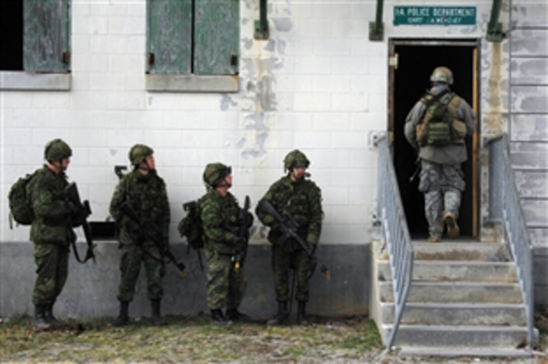 A U.S special forces soldier enters a building at a military operations in urban terrain training site while Canadian soldiers prepare themselves to react during exercise Southbound Trooper IX on Fort Pickett, Va., Feb. 19, 2009. The U.S. sodier is assigned to Company A, 3rd Battalion, 3rd Special Forces Group, and the Canadian allies are part of the 45th Field Engineer Squadron.