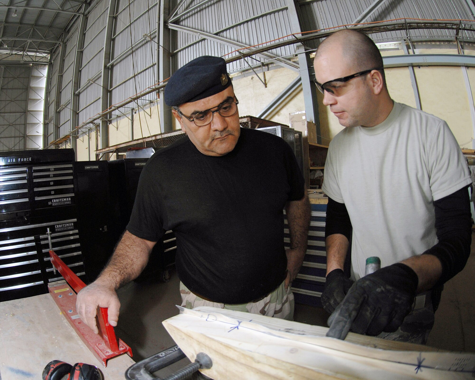 Tech. Sgt. Bobby McKenzie explains how to hand form a piece of sheet metal in the shape of an aircraft rib using forming blocks to one of his Iraqi students Feb. 20 at Sather Air Base, Iraq. Sergeant McKenzie is a 321st Air Expeditionary Advisory Squadron aircraft structural maintenance adviser deployed from Little Rock Air Force Base, Ark. He is a native of Manchester, Tenn. (U.S. Air Force photo/Staff Sgt. Tim Beckham) 
