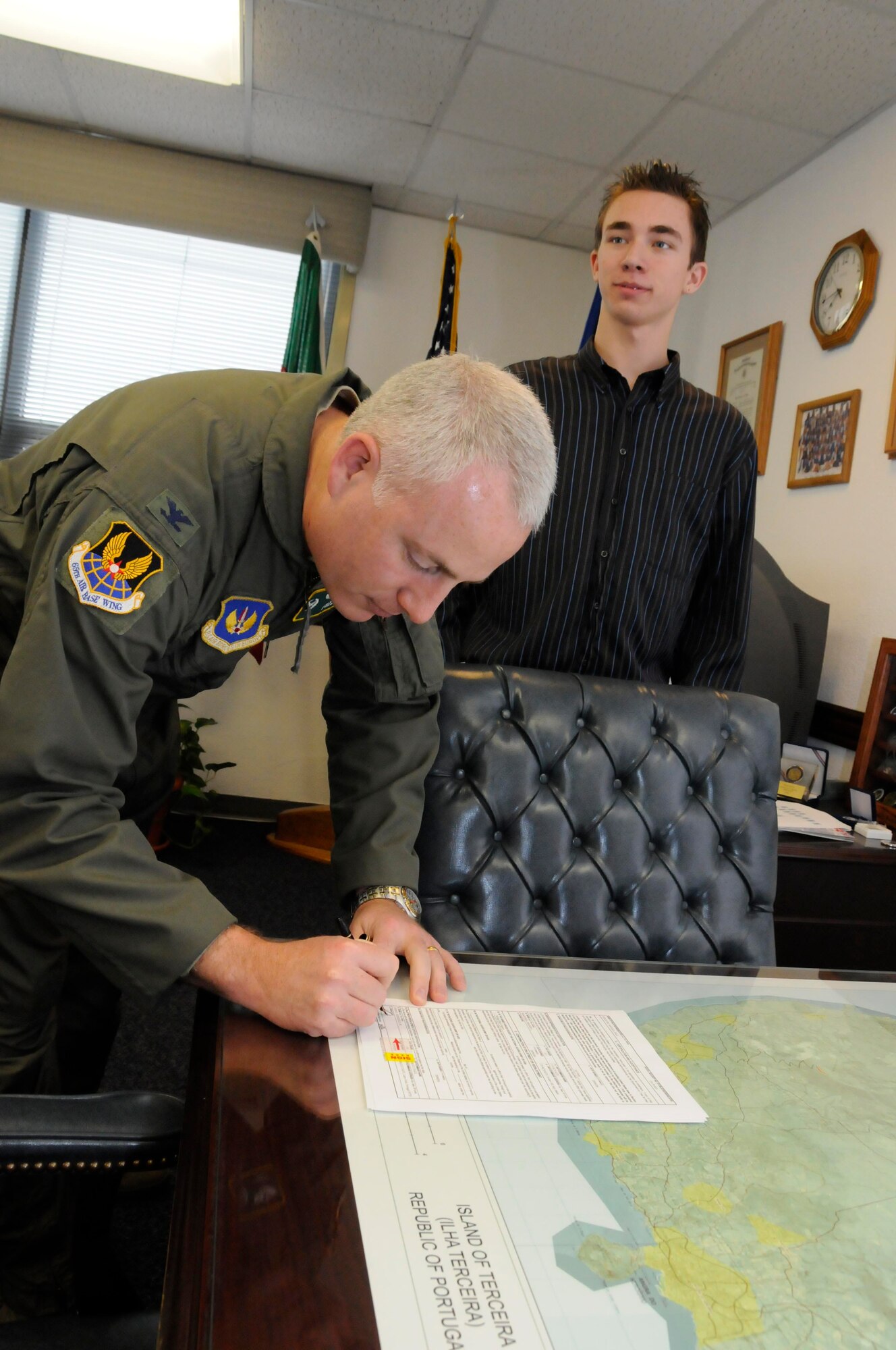 Col. Roderick Dorsey, 65th Mission Support Group commander, signs the paperwork after administering the oath of enlistment to Michael Longacre in a ceremony here Feb. 6.  Michael, soon-to-be Air Force member and son of Chief Kenneth Longacre, 65th MSS, took the oath of enlistment into the Delayed Enlistment Program here after deciding he would like to join the Air Force and follow in his father’s footsteps.  (Photo by Guido Melo)
