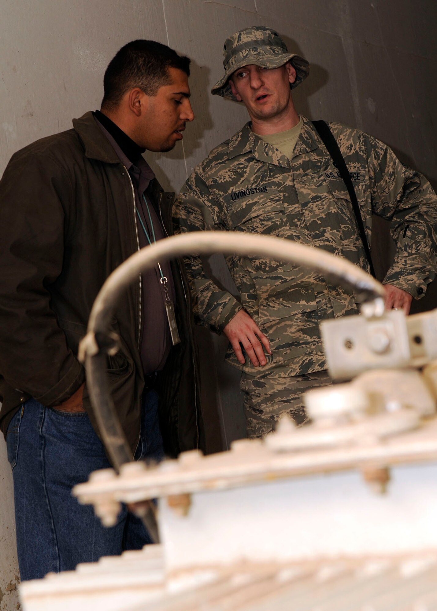 Staff Sgt. Todd Livingston, Joint Area Support Group, talks to Ali, an Iraqi contractor, about what has to happen for the switch from generators to commercial power Baghdad Feb. 14. The switch over took place Feb. 20.  Sergeant Livingston is a Central electrician deployed from Ellsworth Air Force Base, S.D. and a native of Rochester Minn.  (U.S. Air Force photo by Senior Airman Jacqueline Romero) 