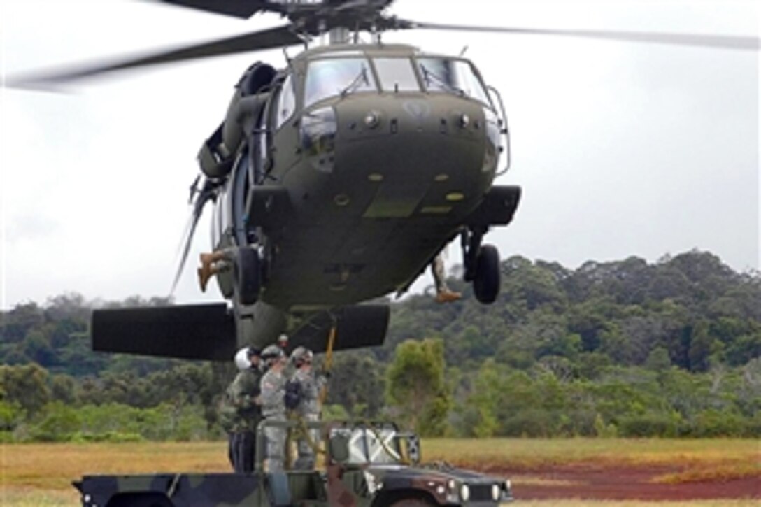 An instructor with a sling-load certification course guides U.S. Army soldiers as a load is slung to a UH-60L Black Hawk helicopter on Schofield Barracks, Hawaii, Feb. 12, 2009. The Black Hawk crew is assigned to Company C, 2nd Battalion, 25th Aviation Regiment, 25th Combat Aviation Brigade.