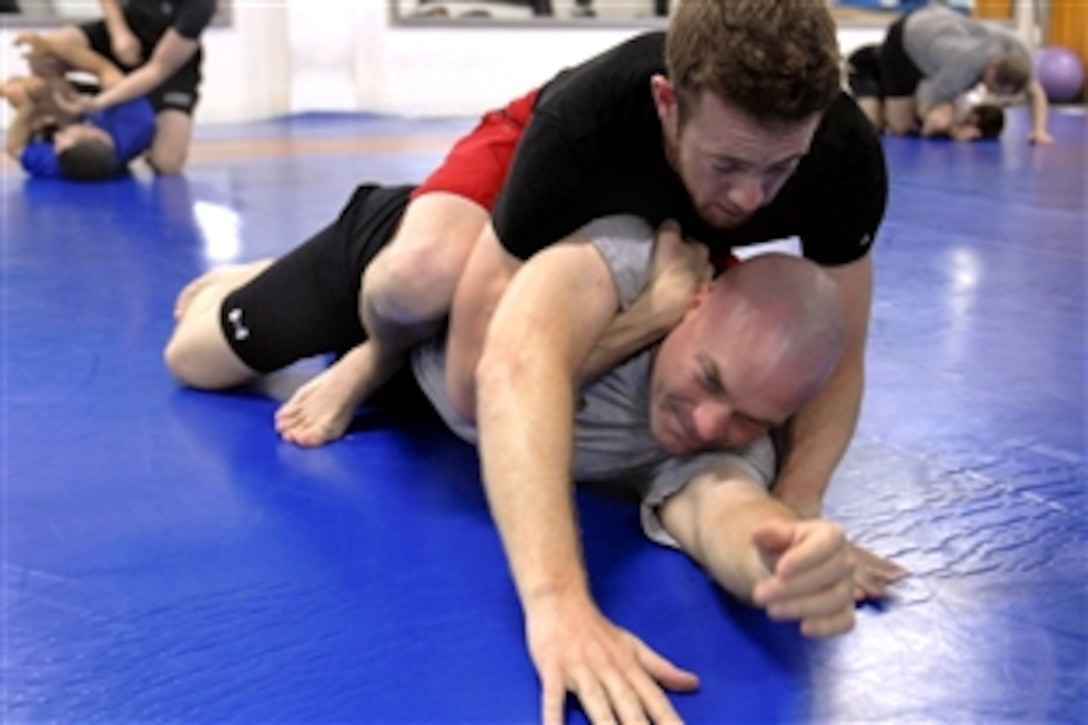 U.S. Army Sgt. John Gaynor, a communications noncommissioned officer, is restrained by Sean McManus, a civilian information technology contractor, during rolling drills on Camp Victory, Iraq, Feb. 20, 2009. This technique is part of the Modern Army Combatives Program.