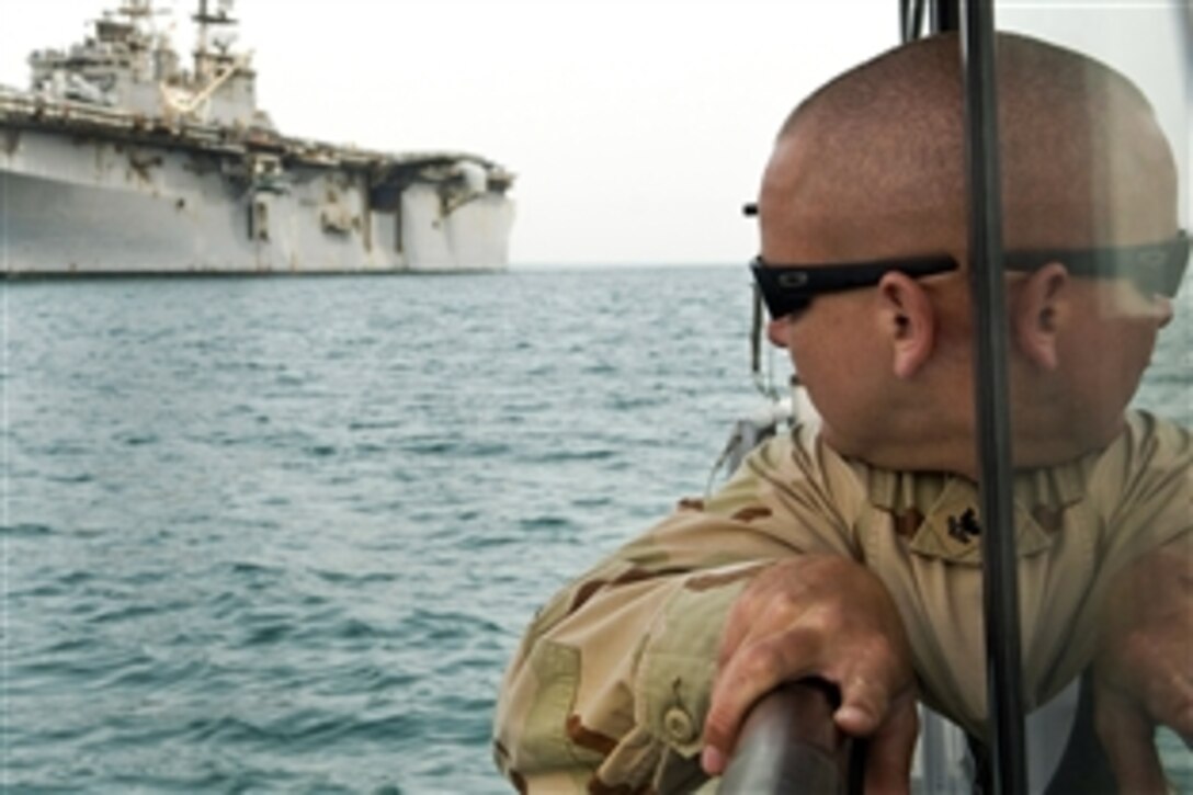 U.S. Navy Petty Officer 2nd Class Robert Cole looks toward the amphibious assault ship USS Iwo Jima while providing port security as it arrives on Kuwait Naval Base, Feb. 14, 2009. Cole is assigned to Martime Expeditionary Squadron 1. 