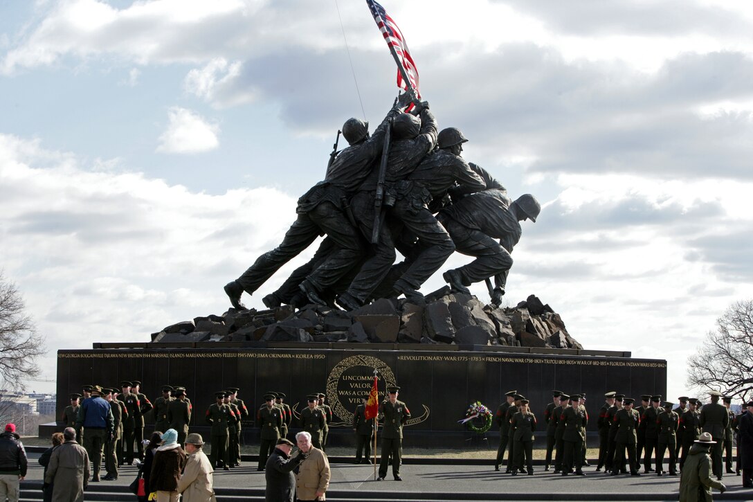 U.S. Marines stationed at Henderson Hall in Arlington, Va., stand at parade rest in front of the Marine Corps War Memorial in Arlington moments before a flag raising ceremony Feb. 23.  Active duty and reserve Marines, Marine veterans, retired Marines and civilian spectators gathered at the memorial, which depicts the five Marines and one Navy corpsman raising the American flag on Mount Suribachi during World War II, to observe the 64th anniversary of the actual flag-raising.