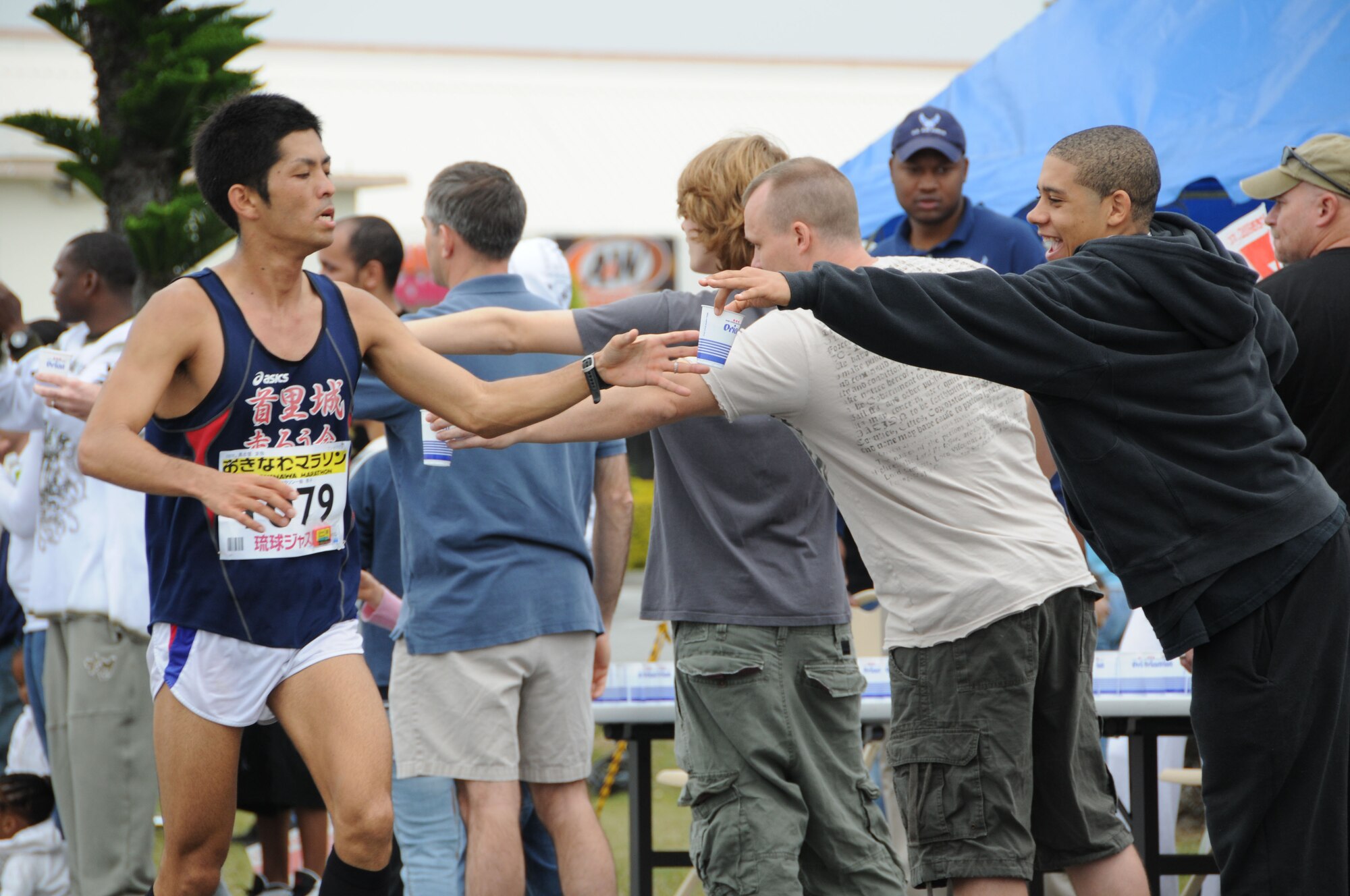Volunteers hand out water to a runner participating in the Okinawa marathon Feb. 22 at Kadena Air Base, Japan. Team Kadena volunteers encouraged and provided water to runners as they participated in the Kadena Air Base portion of the marathon. (U.S. Air Force Photo/Staff Sgt. Darnell T. Cannady)