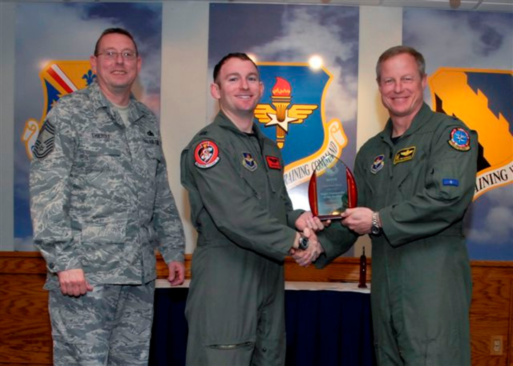 Capt. Brian Wood, 89th Flying Training Squadron, accepts the Flight Commander of the Quarter Award, for the first quarter from Col. David Petersen, commander of the 80th Flying Training Wing at the wing's quarterly award luncheon. Also pictured is 80th FTW Superintendant Chief Master Sgt. Norman Thierolf. (U.S. Air Force photo)