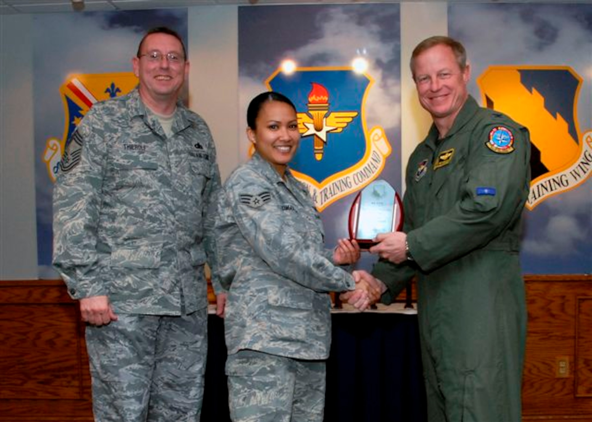 Senior Airman Dayenesha Bumanglag accepts the Airman of the Quarter Award for the first quarter from Col. David Petersen, commander of the 80th Flying Training Wing at the wing's quarterly award luncheon. Also pictured is 80th FTW Superintendant Chief Master Sgt. Norman Thierolf. (U.S. Air Force photo)