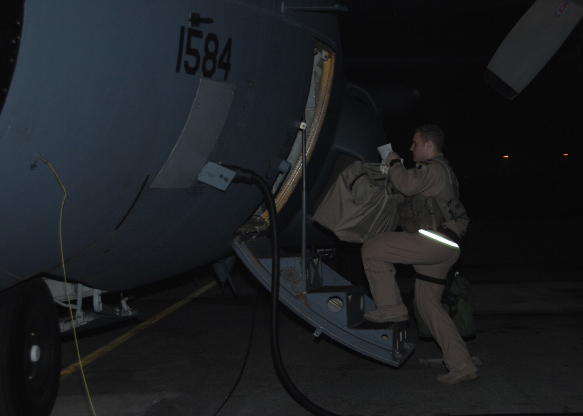 Capt. Quinn Nixon, an EC-130 Compass Call aircraft commander with the 43rd Expeditionary Electronic Combat Squadron, loads his gear onto the aircraft Feb. 16 at an air base in Southwest Asia. During the flight, the aircrew wouild complete the 20,000th combat flight hour for the unit which has had five years of continuous deployment. (U.S. Air Force photo/Senior Airman Courtney Richardson)