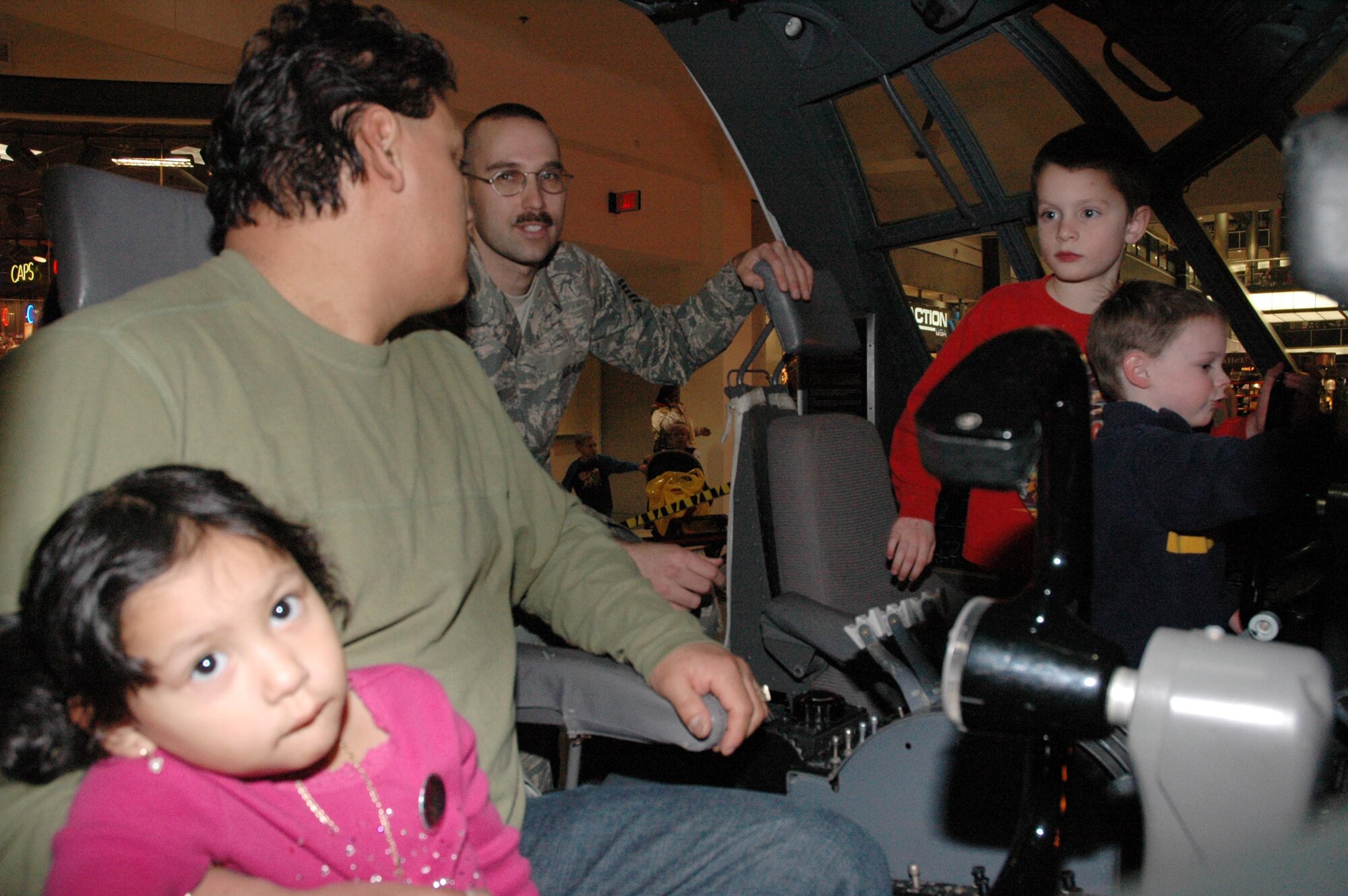 Maritsa Bunay,(3) Miguel Bunay, Mason Phair, (6) and Ryan Phair,(3) play inside the 934th Airlift Wing flight deck display while Tech. Sgt. Clint Hamann, 934th Maintenance Squadron, talks about the Air Force at the Mall of America during the annual Government on Display exhibit. (Air Force Photo/Tech. Sgt. Bob Sommer)