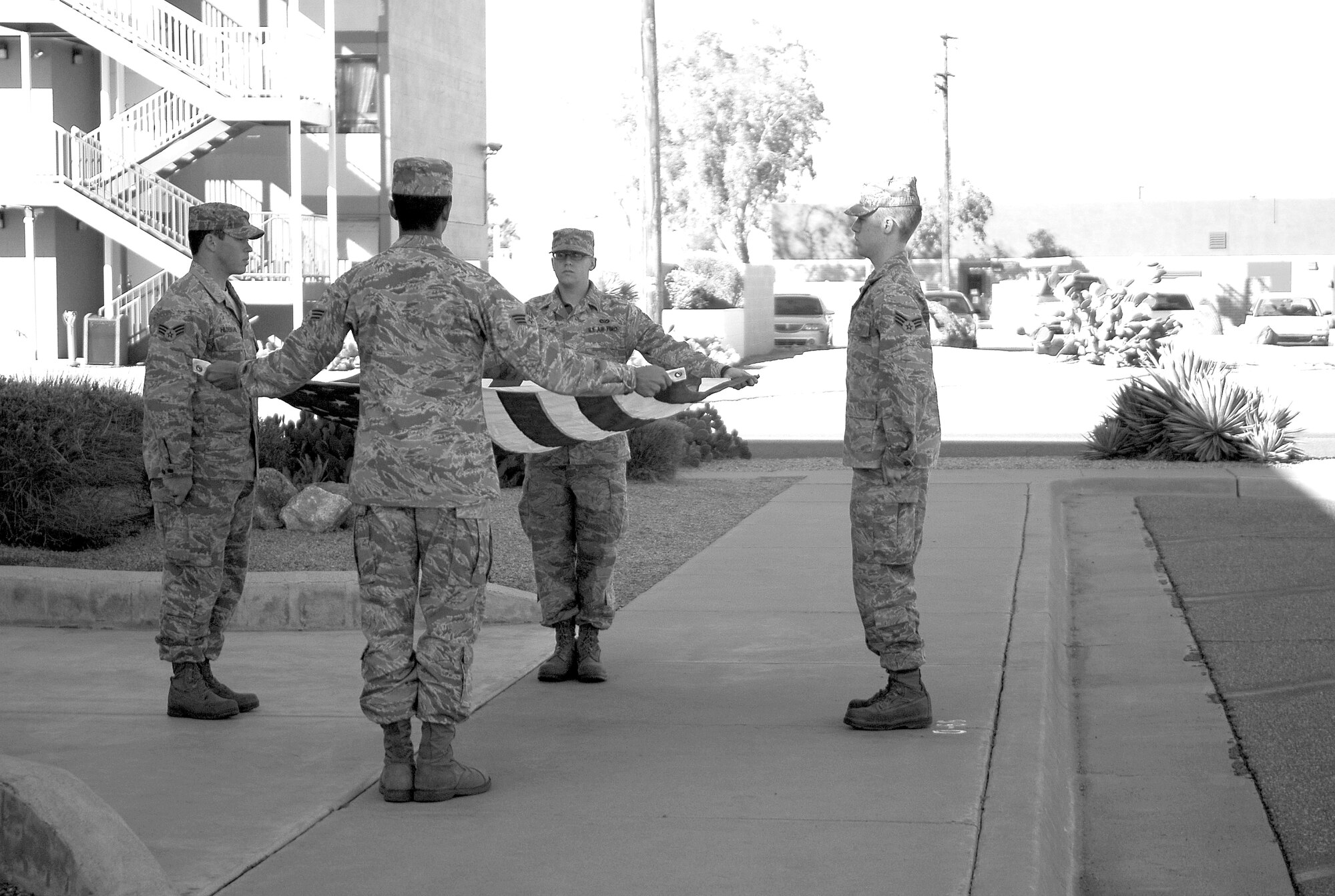 Airmen of the John J. Rhodes Airman Leadership School Class 09-3 fold a flag flown over the ALS building. The flag was included in a shadow box presented to the wife of the late Master Sgt. Randy Gillespie, a Luke fuels technician killed while serving in Afghanistan in 2007.(U.S. Air Force photo/2nd Lt. Bryan Bouchard) 
