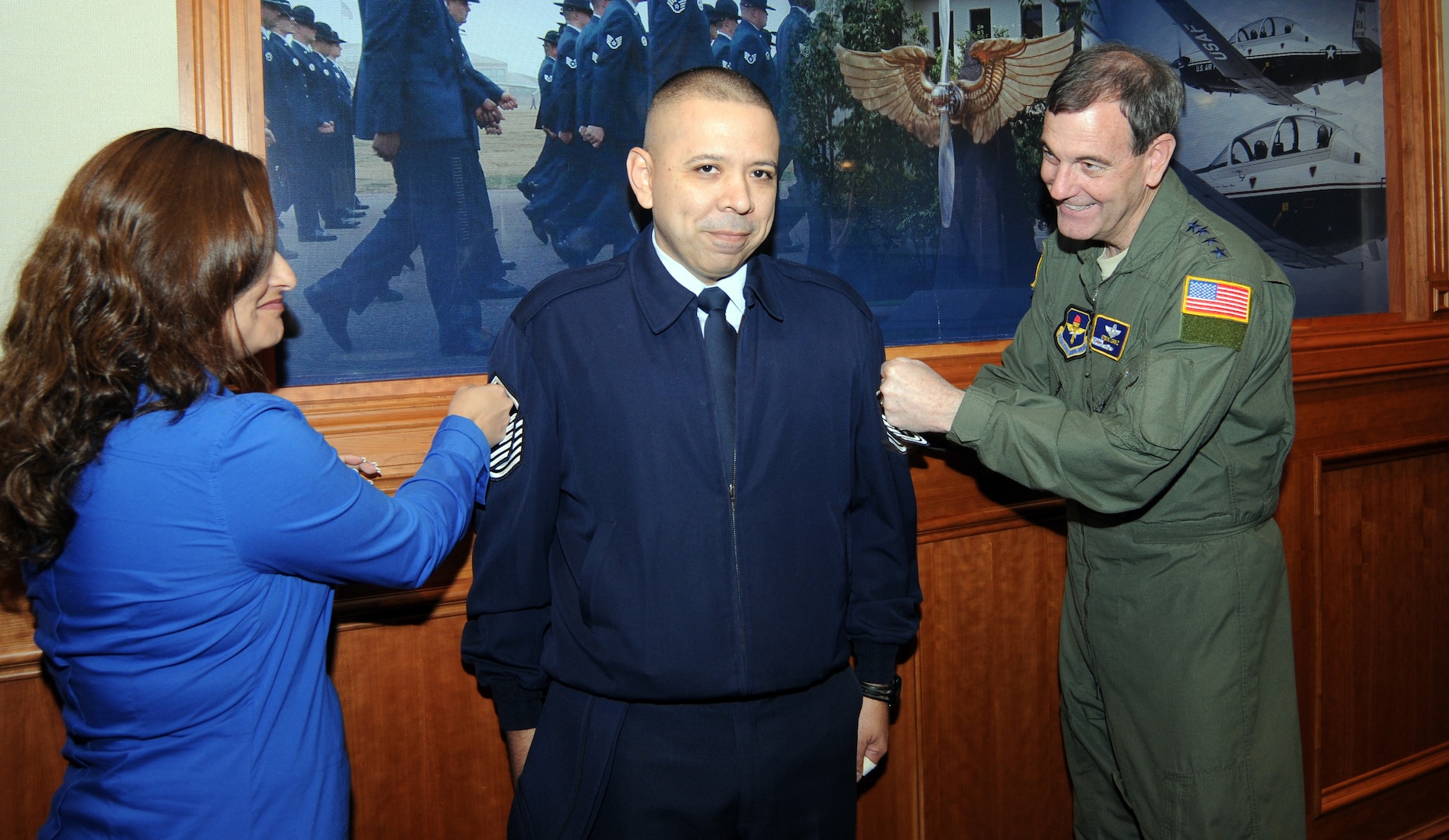 Tech. Sgt. Juan Nieves (center), 12th Mission Support Group, braces himself as wife, Maria, and Gen. Stephen Lorenz, Air Education and Training Command commander, tack on his new master sergeant stripes Feb. 23 at AETC headquarters. Sergeant Nieves was selected for promotion from more than a dozen technical sergeants nominated from all over the command under the Stripes To Exceptional Performers, or STEP, promotion program. (U.S. Air Force photo by Rich McFadden)