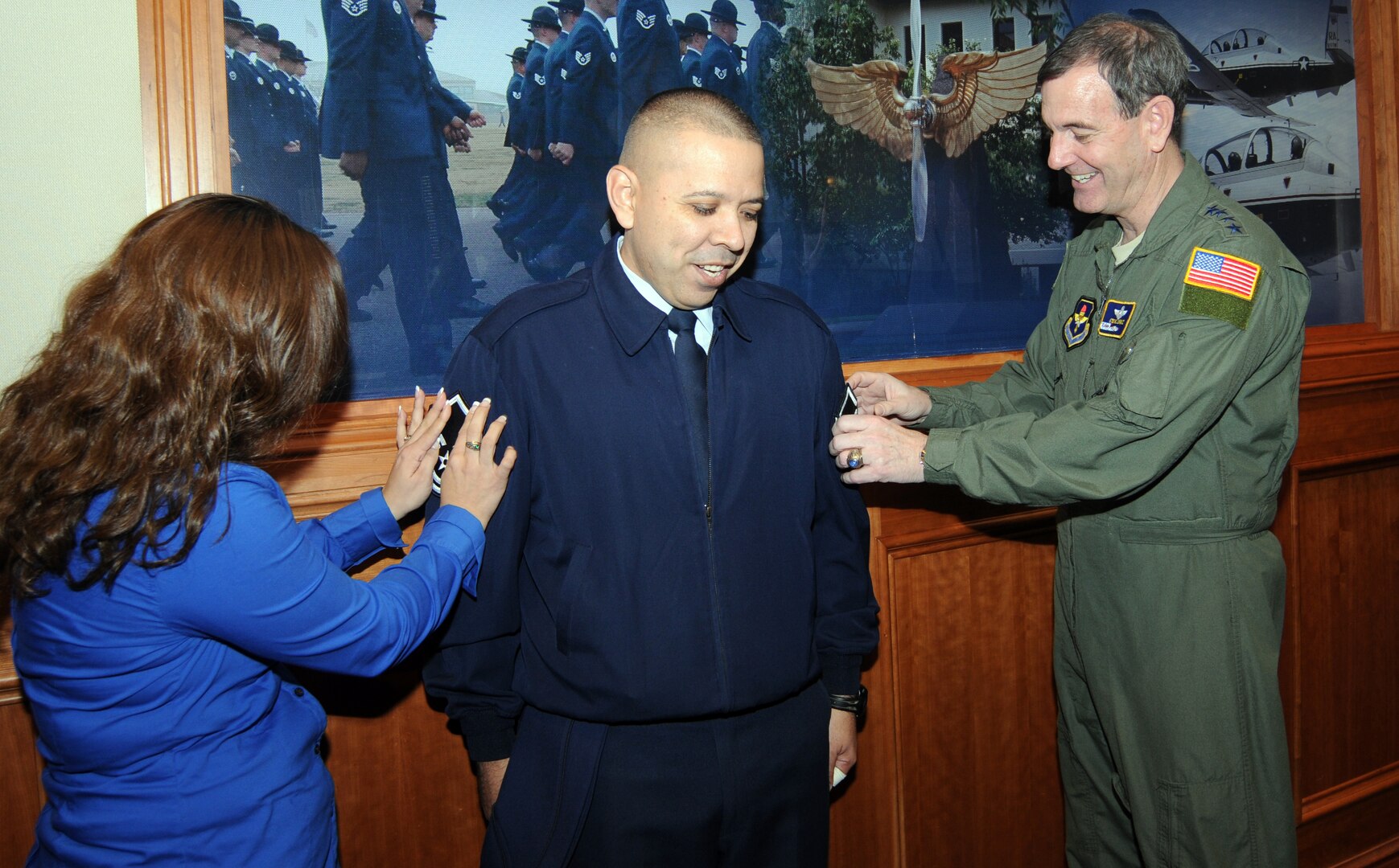 Tech. Sgt. Juan Nieves (center), 12th Mission Support Group, braces himself as wife, Maria, and Gen. Stephen Lorenz, Air Education and Training Command commander, tack on his new master sergeant stripes Feb. 23 at AETC headquarters. Sergeant Nieves was selected for promotion from more than a dozen technical sergeants nominated from all over the command under the Stripes To Exceptional Performers, or STEP, promotion program. (U.S. Air Force photo by Rich McFadden)