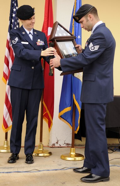 Staff Sgt. Laura Magas , 39th Security Forces Squadron military working dog handler, presents a personal gift from the “handlers” to Staff Sgt. Chris Smith, 39th SFS MWD handler, in memory of the late MWD Bak, Feb. 20 at the MWD memorial ceremony held at the 39 SFS K-9 kennels. (U.S. Air Force photo by Airman 1st Class Amber Russell)