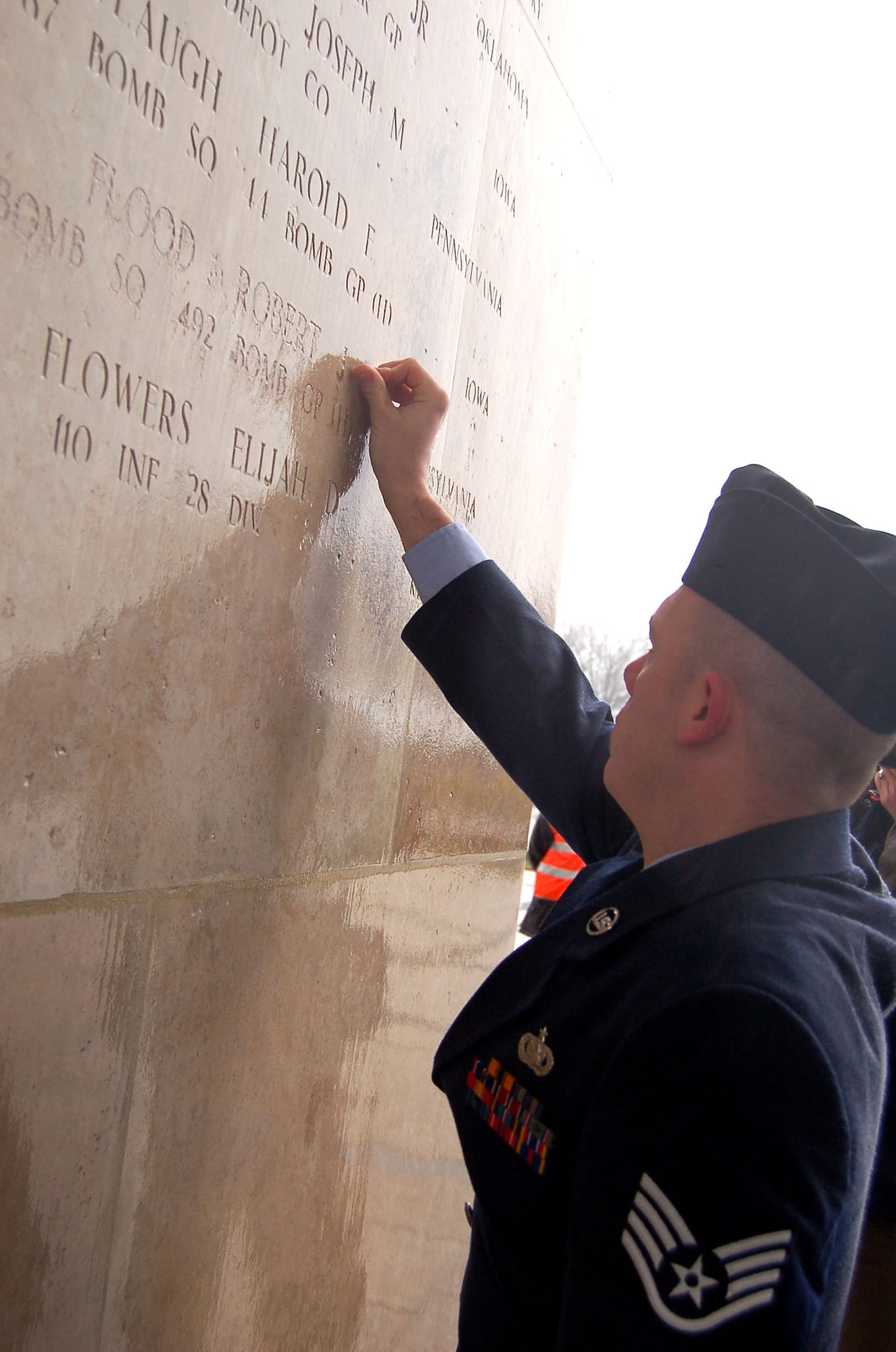 HENRI-CHAPELLE, Belgium -- Staff Sgt. Waylon Ross, integrated command and control lead system administrator for the NATO Programming Centre, places a rosette next to Staff Sgt. Robert J. Flood’s name Feb. 20, 2009 at the Henri-Chapelle Cemetery and Memorial in Belgium, signifying he is no longer missing in action. Sergeant Flood was a Pennsylvania native and one of nine men with the McMurray Crew in the Army Air Corps, who flew a B-24 bomber during World War II. (U.S. Air Force photo by 2nd Lt. Kathleen Polesnak)