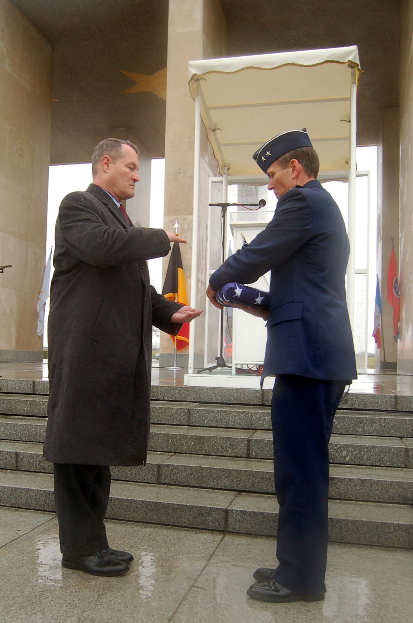 HENRI-CHAPELLE, Belgium -- Maj. Gen. Thomas B. Wright, operations deputy chief of staff of operations for Supreme Headquarters Allied Powers Europe, NATO, hands a folded flag to U.S. Army Retired Brig. Gen. Steven R. Hawkins, director of the European region for the American Battle Monuments Commission, to pay respects to the nine fallen Airmen of the McMurray Crew in the Army Air Corps, who are no longer missing in action. The B-24 bomber crew’s remains were discovered after more than 60 years in a field southwest of Berlin. (U.S. Air Force photo by 2nd Lt. Kathleen Polesnak)