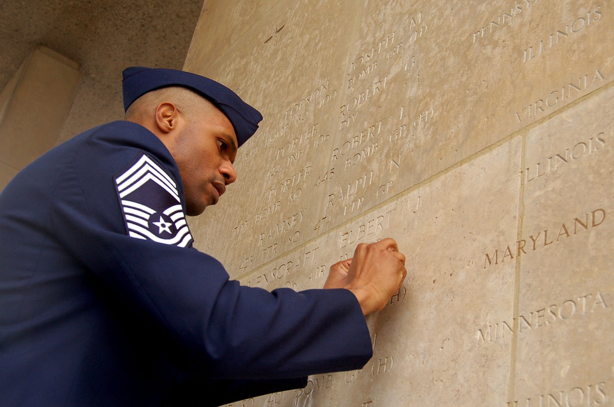 HENRI-CHAPELLE, Belgium -- Chief Master Sgt. Kenneth Williams, U.S. Air Force senior enlisted leaser for Supreme Headquarters Allied Powers Europe, places a rosette next to Tech. Sgt. Leonard J. Ray's engraved name Feb. 20, 2009 at the Henri-Chapelle Cemetery and Memorial in Belgium, signifying he is no longer missing in action. Sergeant Ray was part of the McMurray Crew in the Army Air Corps, which flew a B-24 bomber during World War II. (U.S. Air Force photo by 2nd Lt. Kathleen Polesnak)