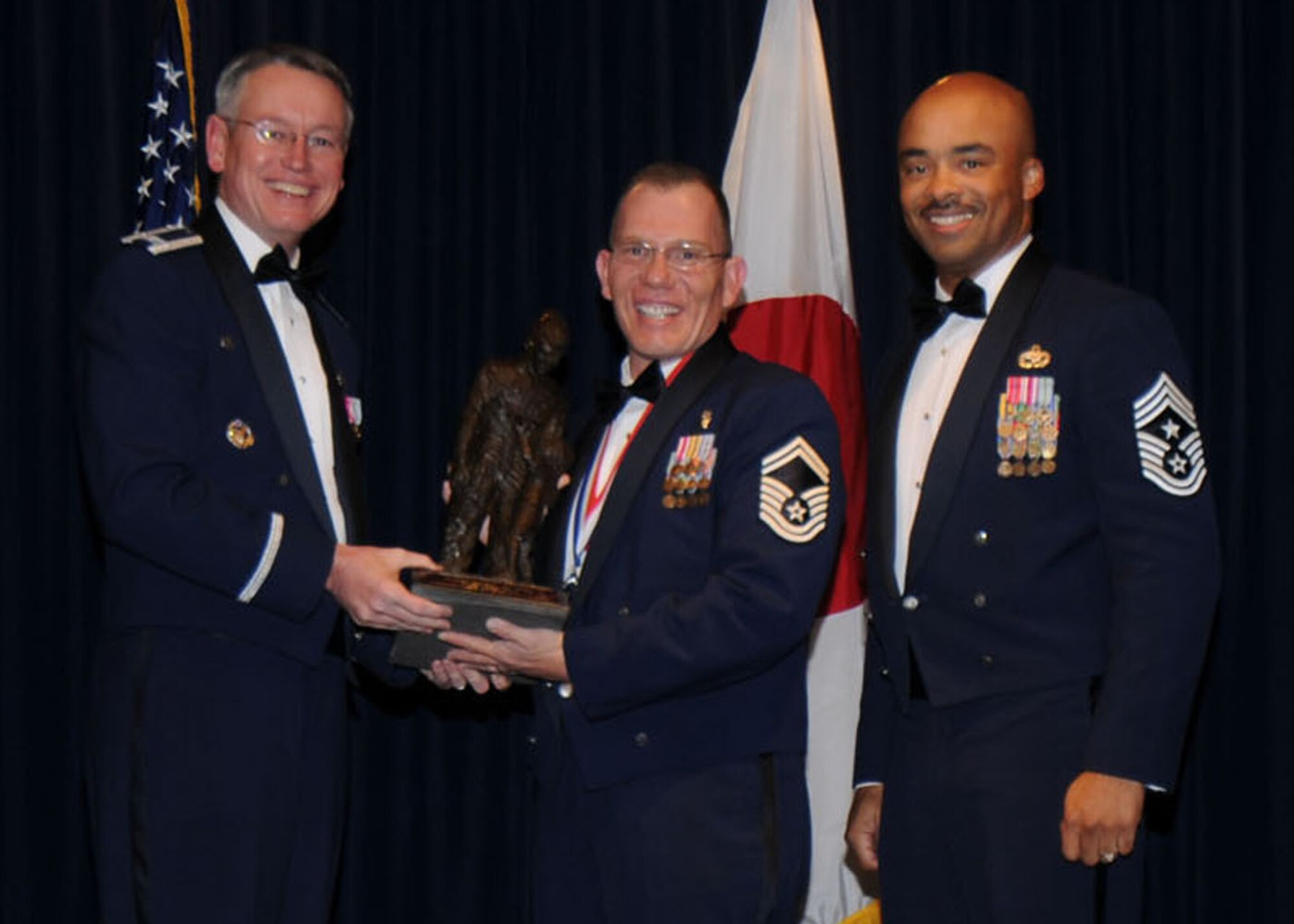 YOKOTA AIR BASE, Japan -- Colonel Jeff Newell, 374th Airlift Wing commander, and Chief Master Sgt. Linus Jordan, 374th AW command chief master sergeant, present Senior Master Sgt. Joshua M. Mills, center, with the 374th AW Senior NCO of the Year award Feb. 21. Sergeant Mills is assigned to the 374th Medical Support Squadron. (U.S. Air Force photo/Senior Airman Veronica Pierce)
