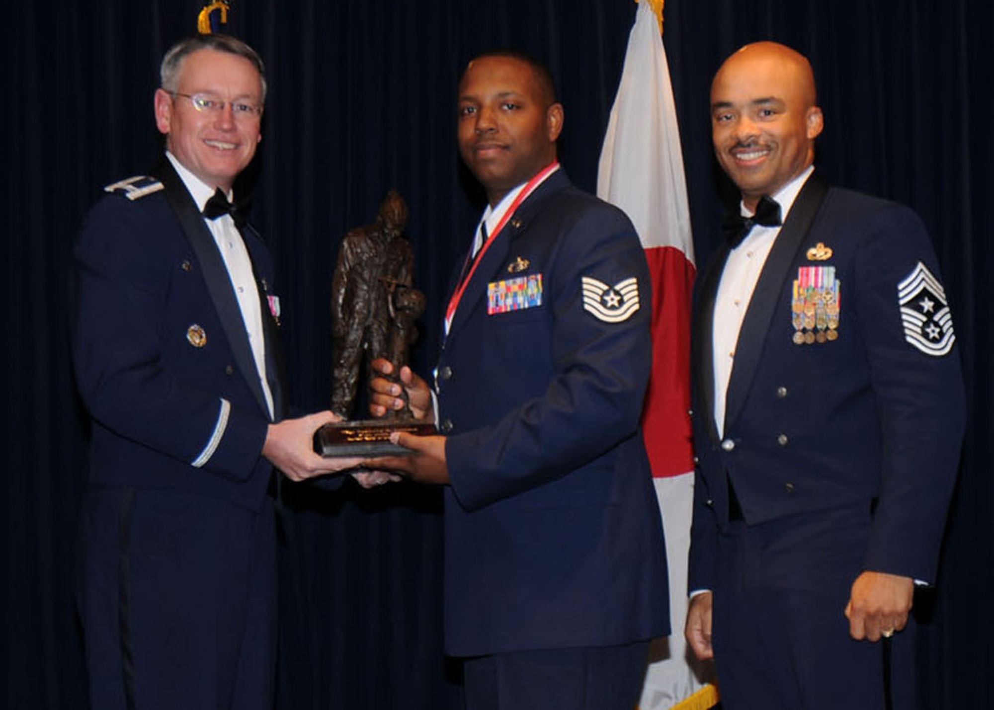 YOKOTA AIR BASE, Japan -- Colonel Jeff Newell, 374th Airlift Wing commander, and Chief Master Sgt. Linus Jordan, 374th AW command chief master sergeant, present Tech. Sgt. Desmond R. Johnson, center, with the NCO of the Year award for tenant unit organizations Feb. 21. Sergeant Johnson is assigned to the 730th Air Mobility Squadron. (U.S. Air Force photo/Senior Airman Veronica Pierce)
