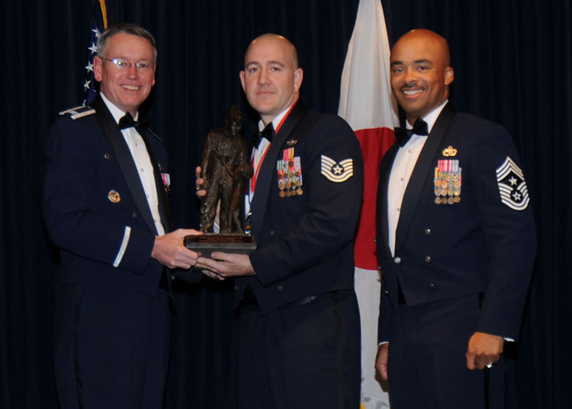 YOKOTA AIR BASE, Japan -- Colonel Jeff Newell, 374th Airlift Wing commander, and Chief Master Sgt. Linus Jordan, 374th AW command chief master sergeant, present Tech. Sgt. Daniel L. Eastwood, center, with the 374th AW NCO of the Year award Feb. 21. Sergeant Eastwood is assigned to the 374th Logistics Readiness Squadron.  (U.S. Air Force photo/ Senior Airman Veronica Pierce)
